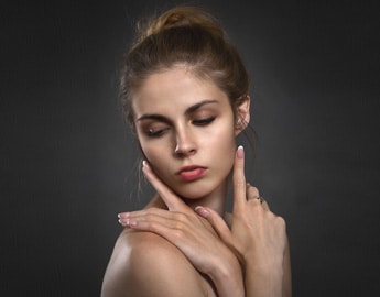 a pretty woman touches her face with her fingers to show the Benefits of the Top Brands Dermal Fillers