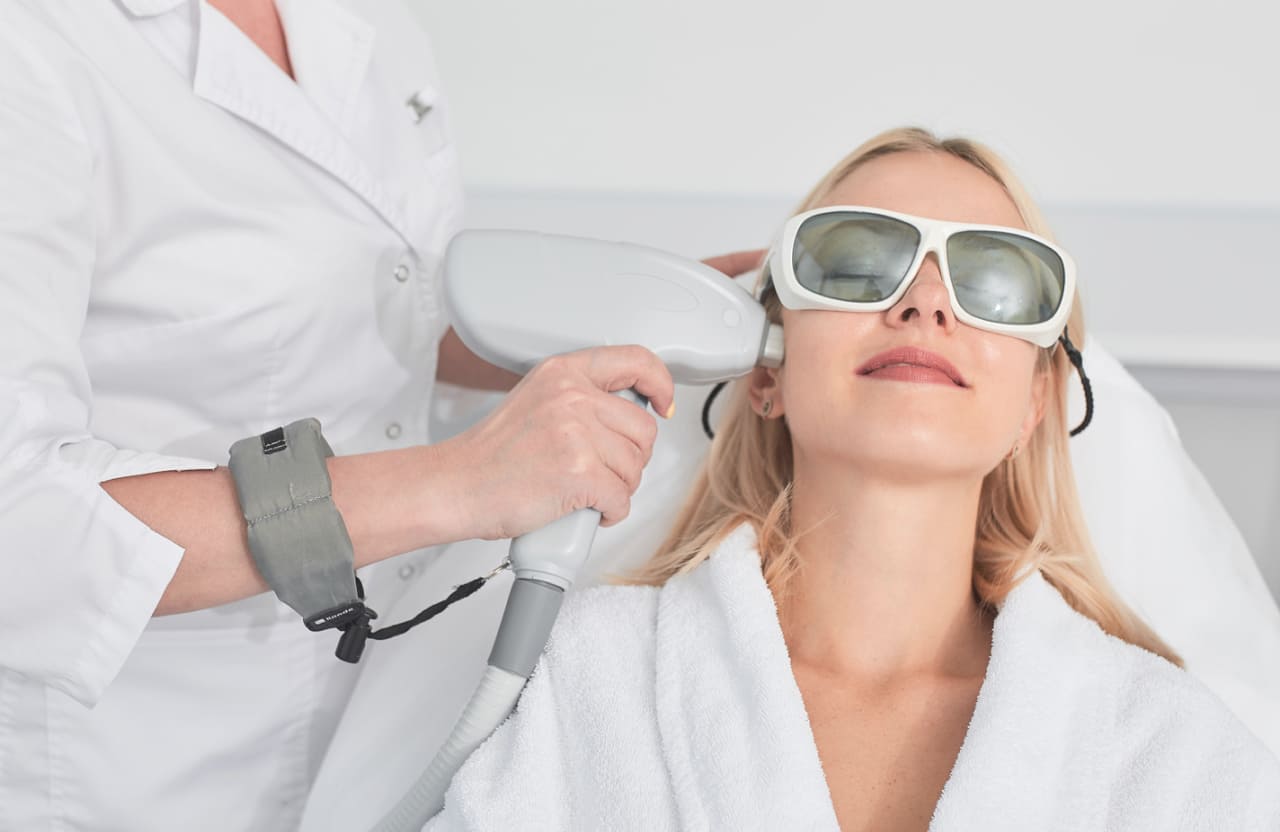 woman wearing shades getting a cosmetic laser treatment on her face