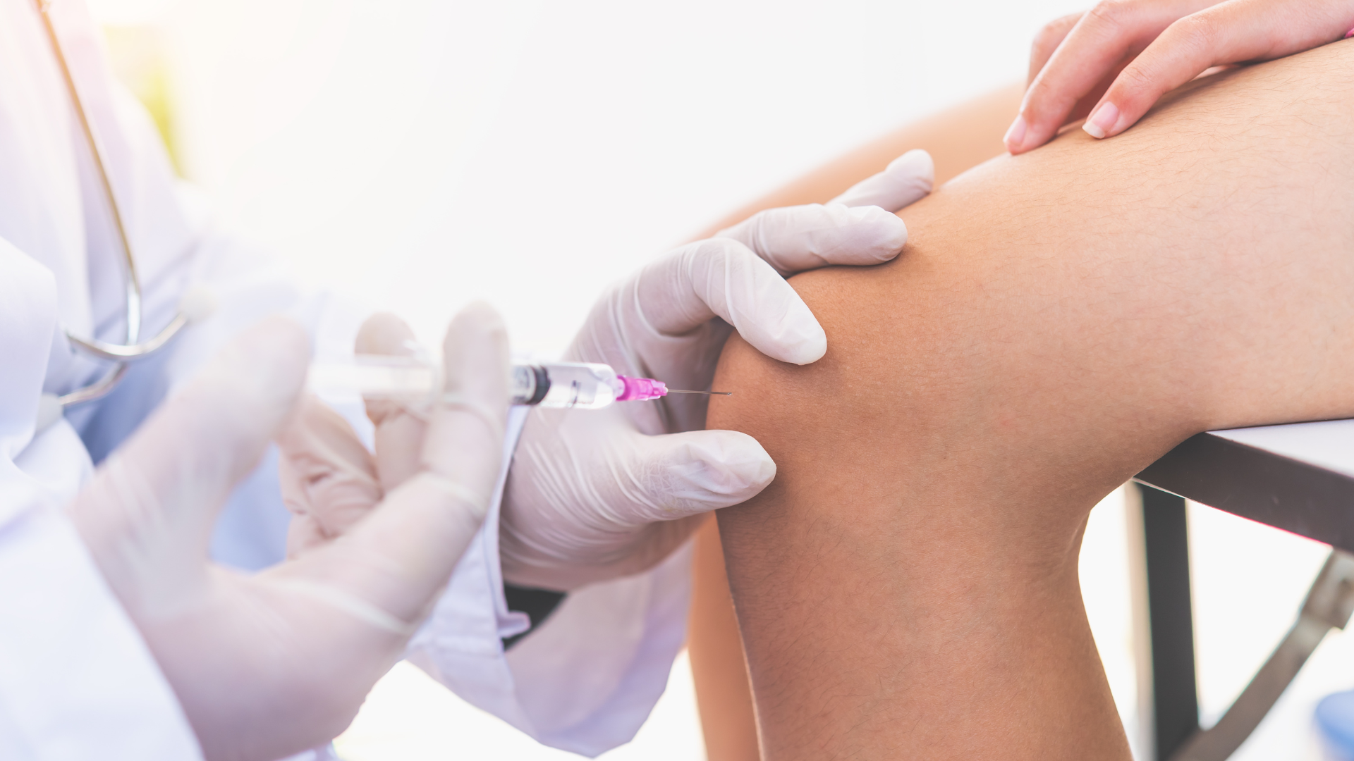 A medical professional administering a knee injection into the patient's joint.