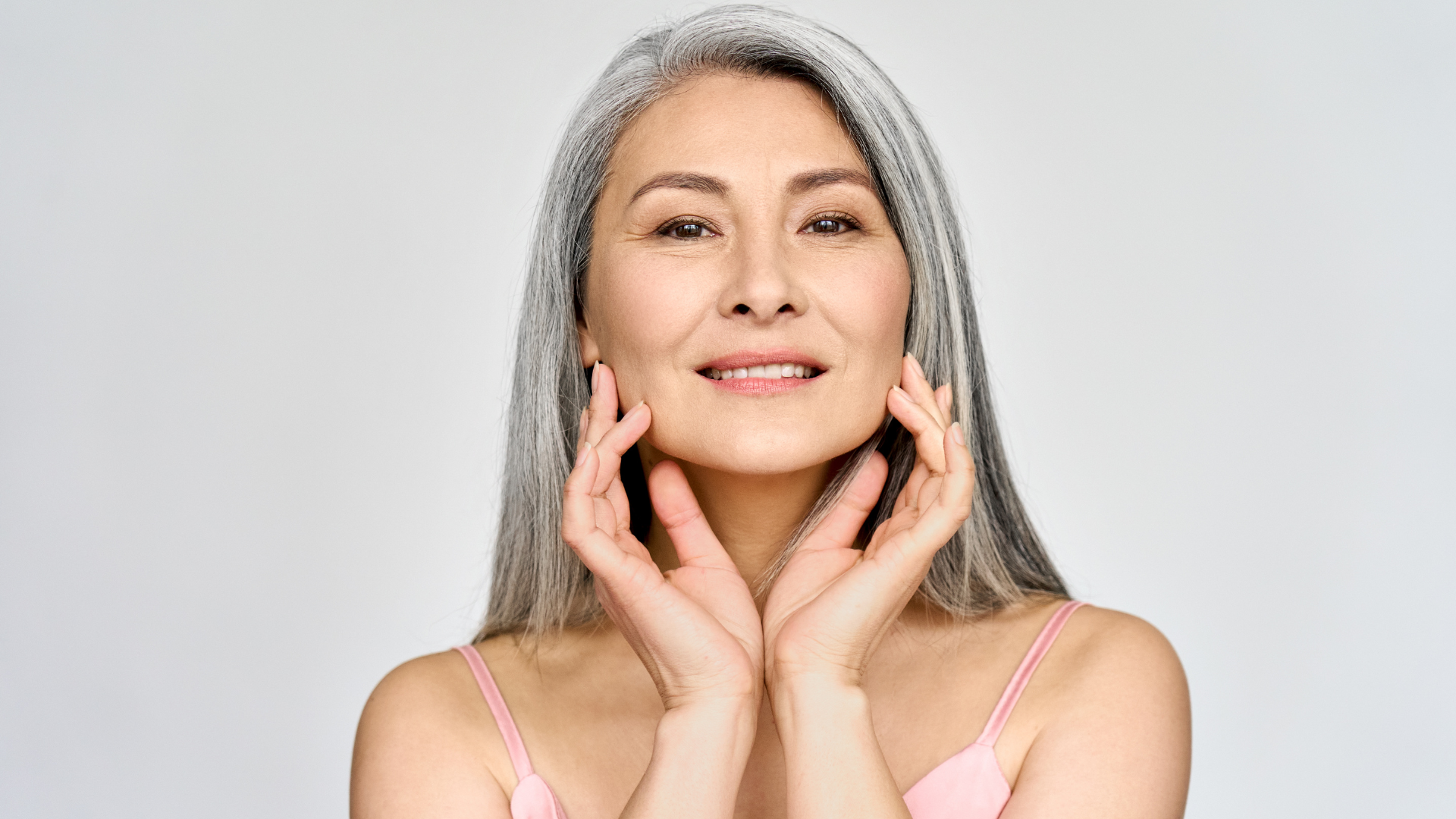 An older woman flexes her rejuvenated facial skin.