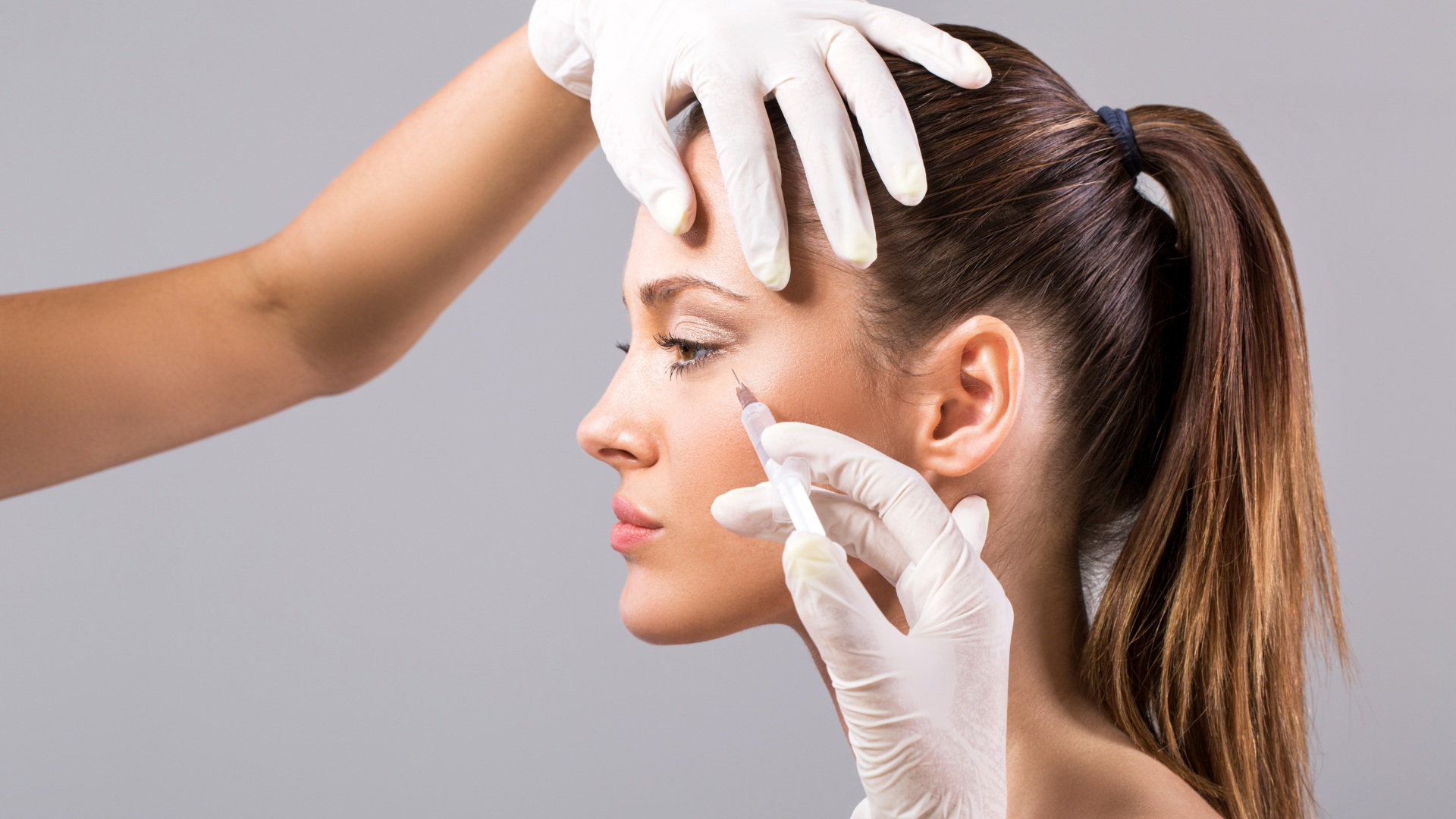 A medical professional administering a Botox injection into the patient's crow's feet.