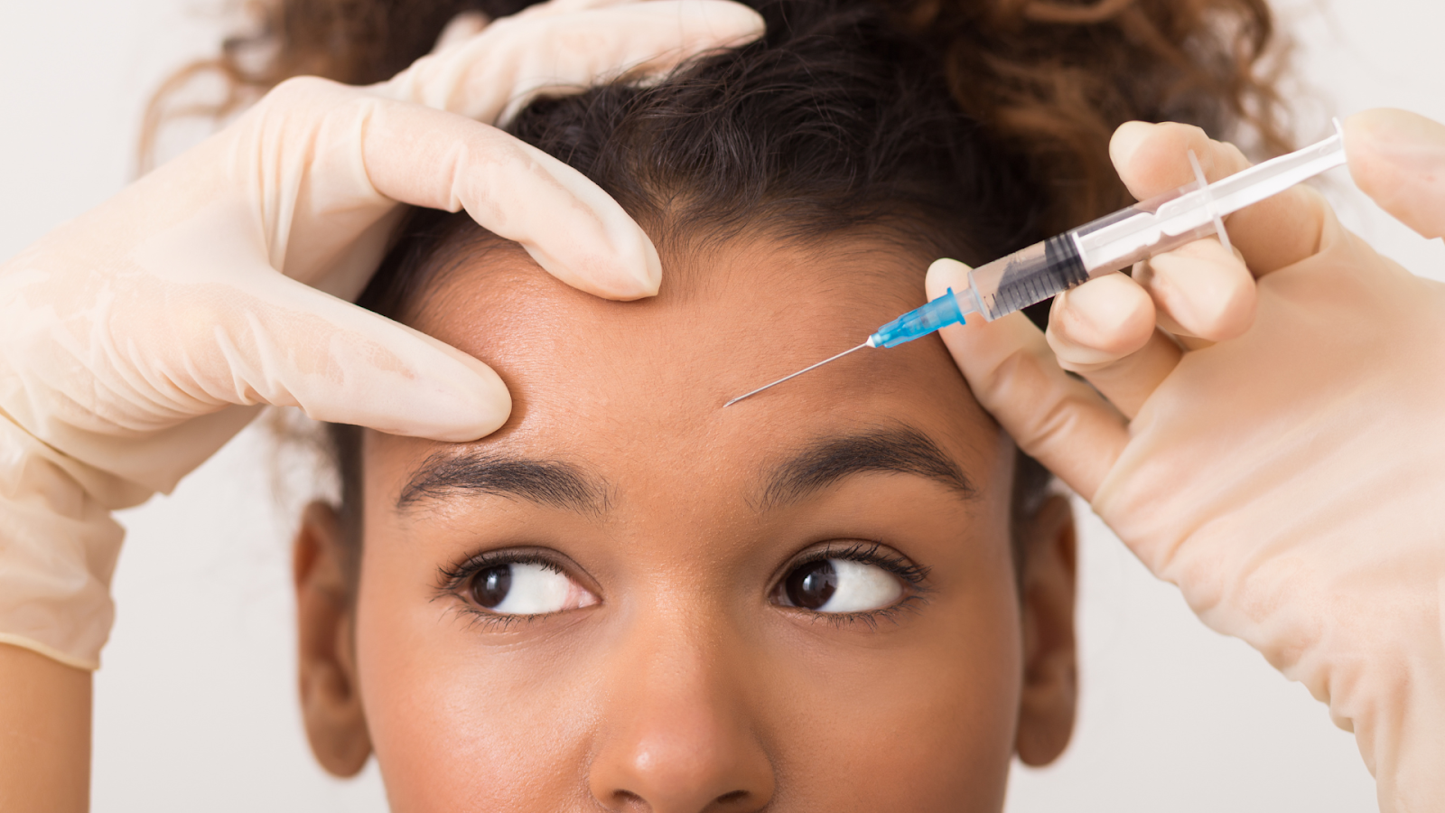 A medical professional administering a Botox injection into the forehead of an individual.