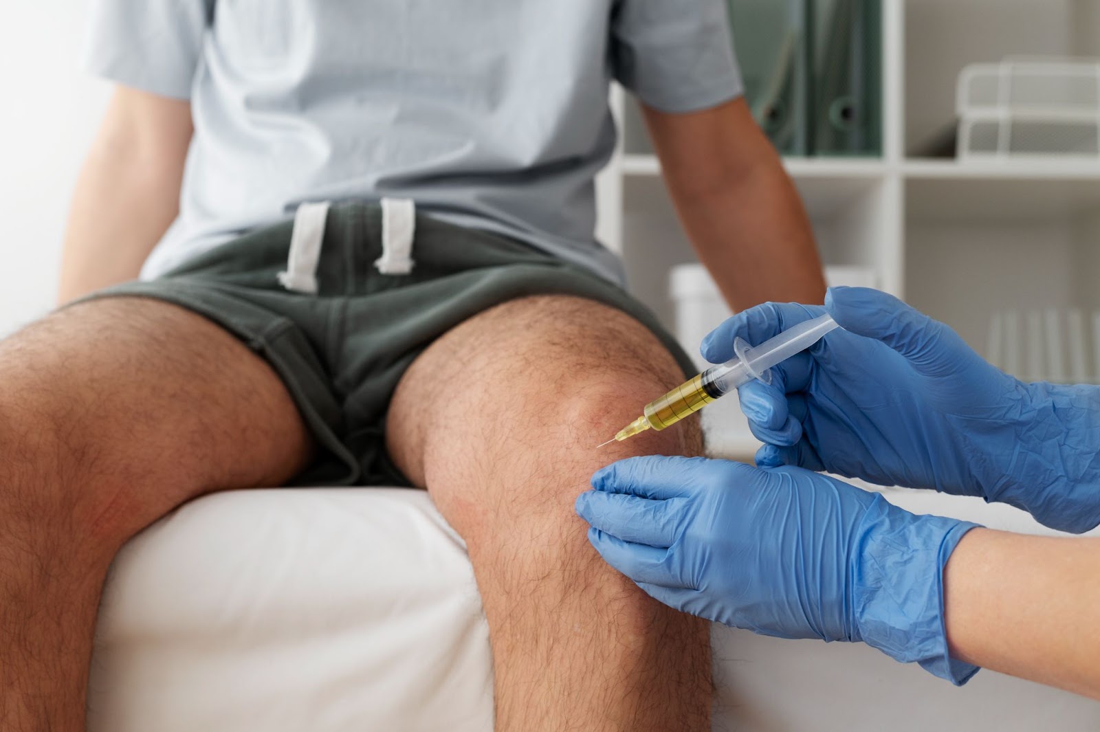 A medical professional injecting a treatment for the patient's knee concerns.