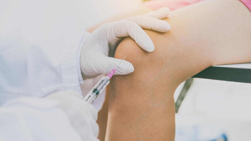 A medical practitioner administering a treatment into a patient's knee.