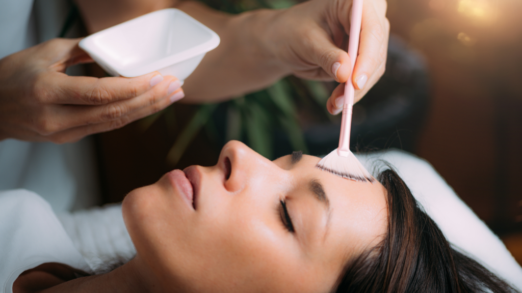 A skin expert treats the woman’s facial skin with a chemical peel.