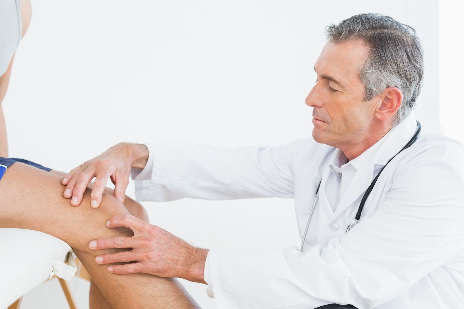 An experienced medical professional checking on an individual's knee.