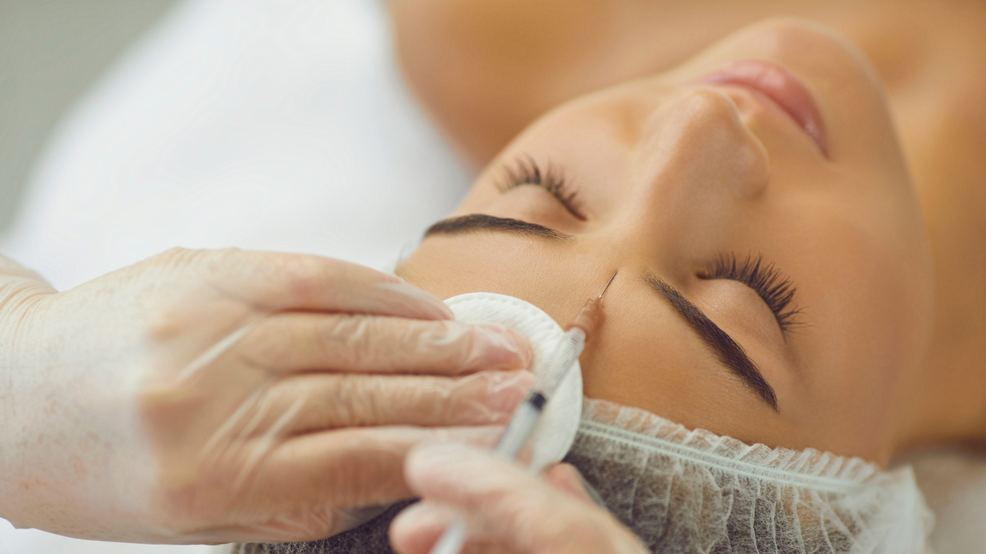 A professional injecting Botox on the area between the eyebrows of the patient.