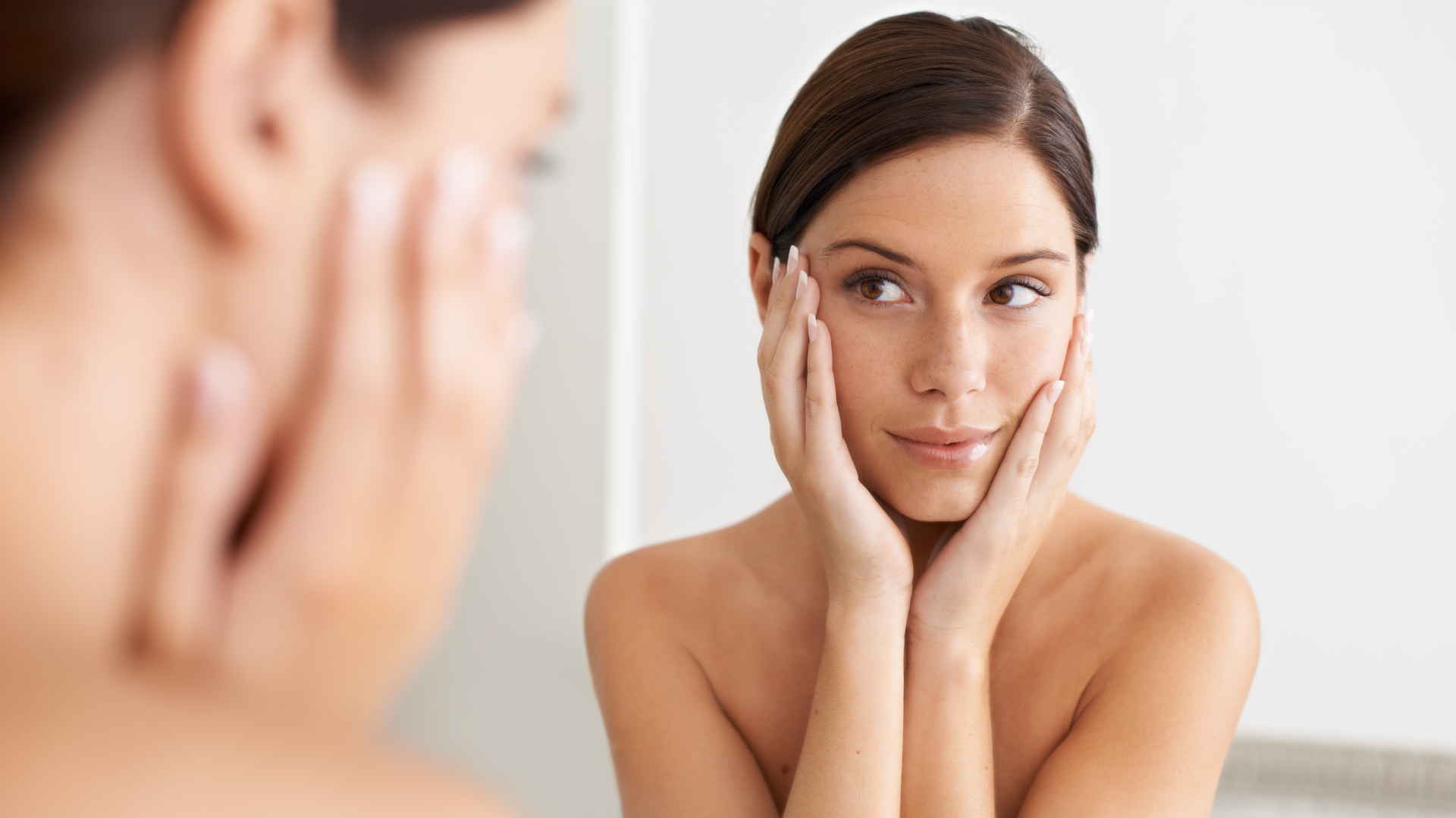 A woman checking out her face in the mirror.