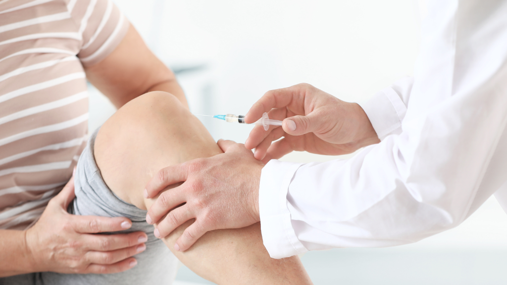 A medical professional administering an injection into the patient's knee.