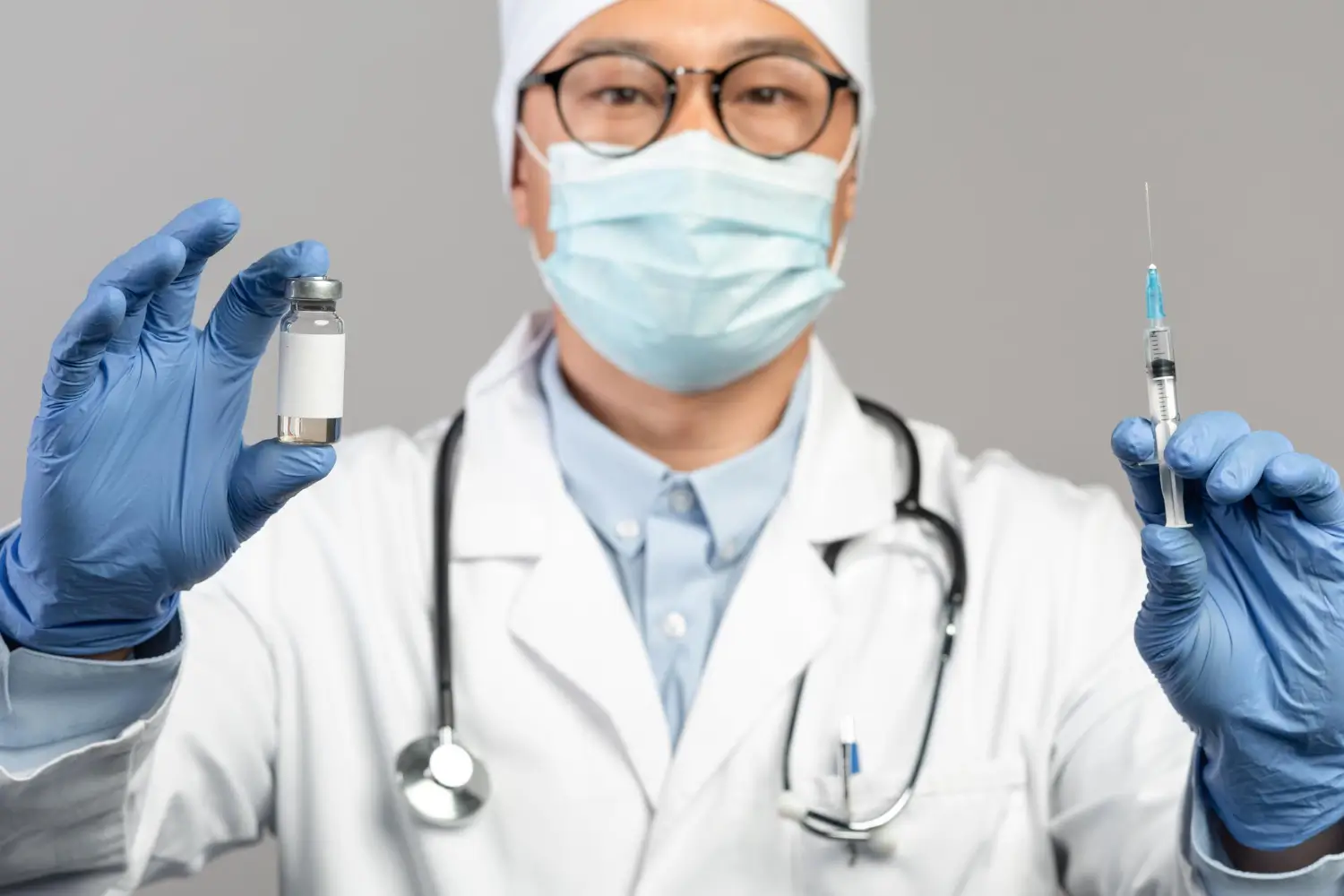 A medical professional holding a medical syringe and vial.