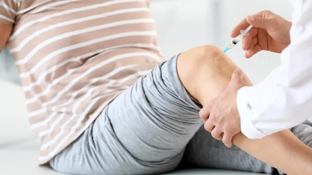 A healthcare provider administering a knee injection.