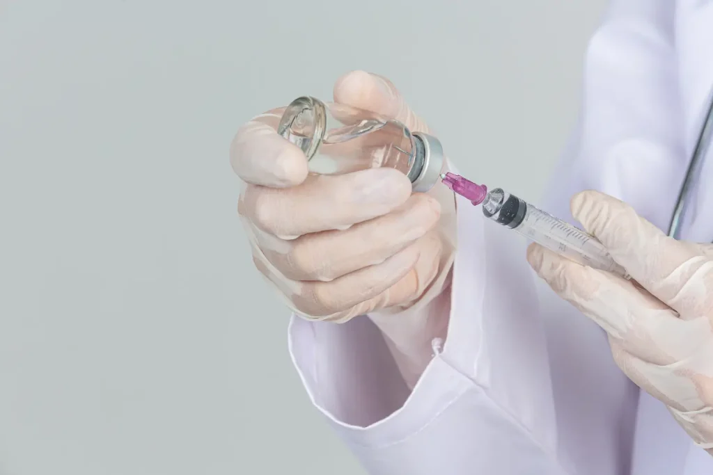 A healthcare provider transferring the vial contents into the syringe.