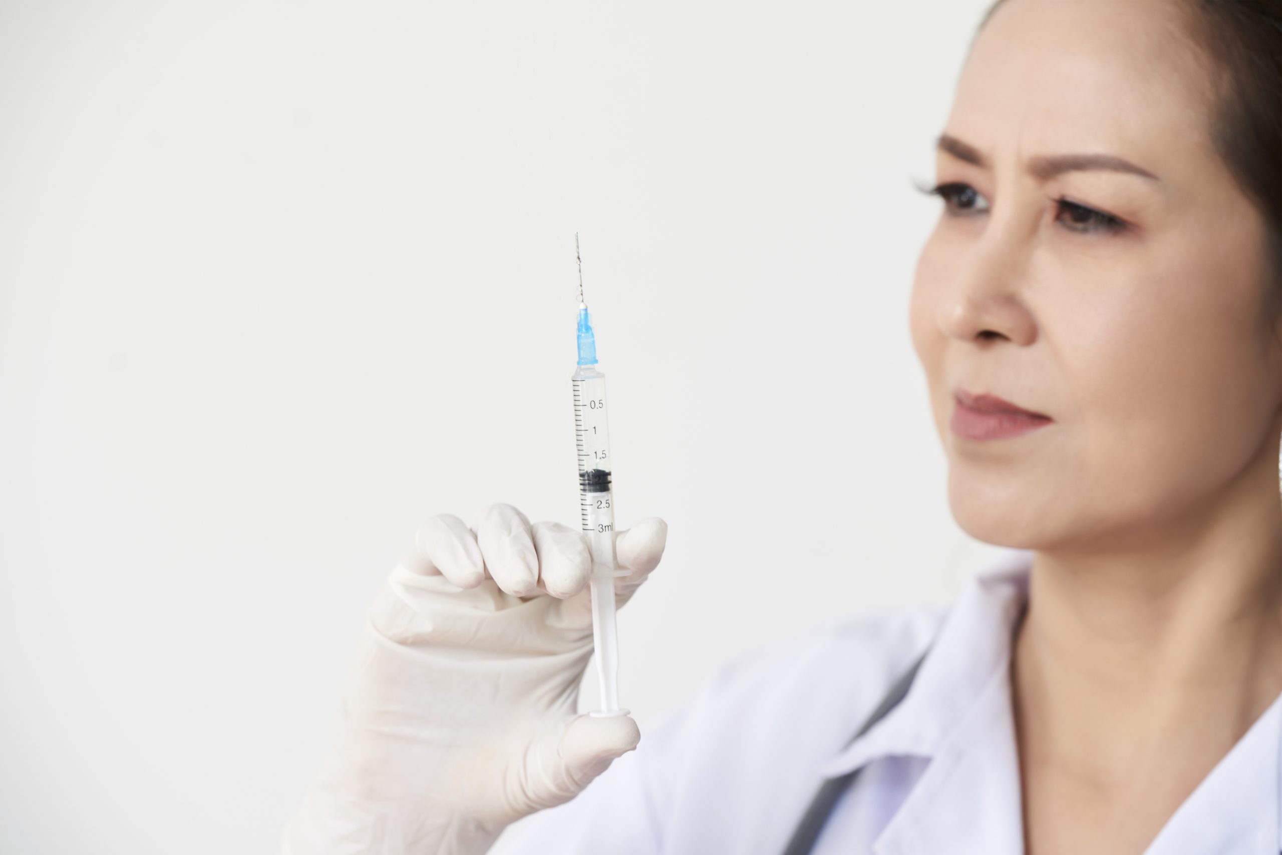 A medical professional holding a medical syringe.