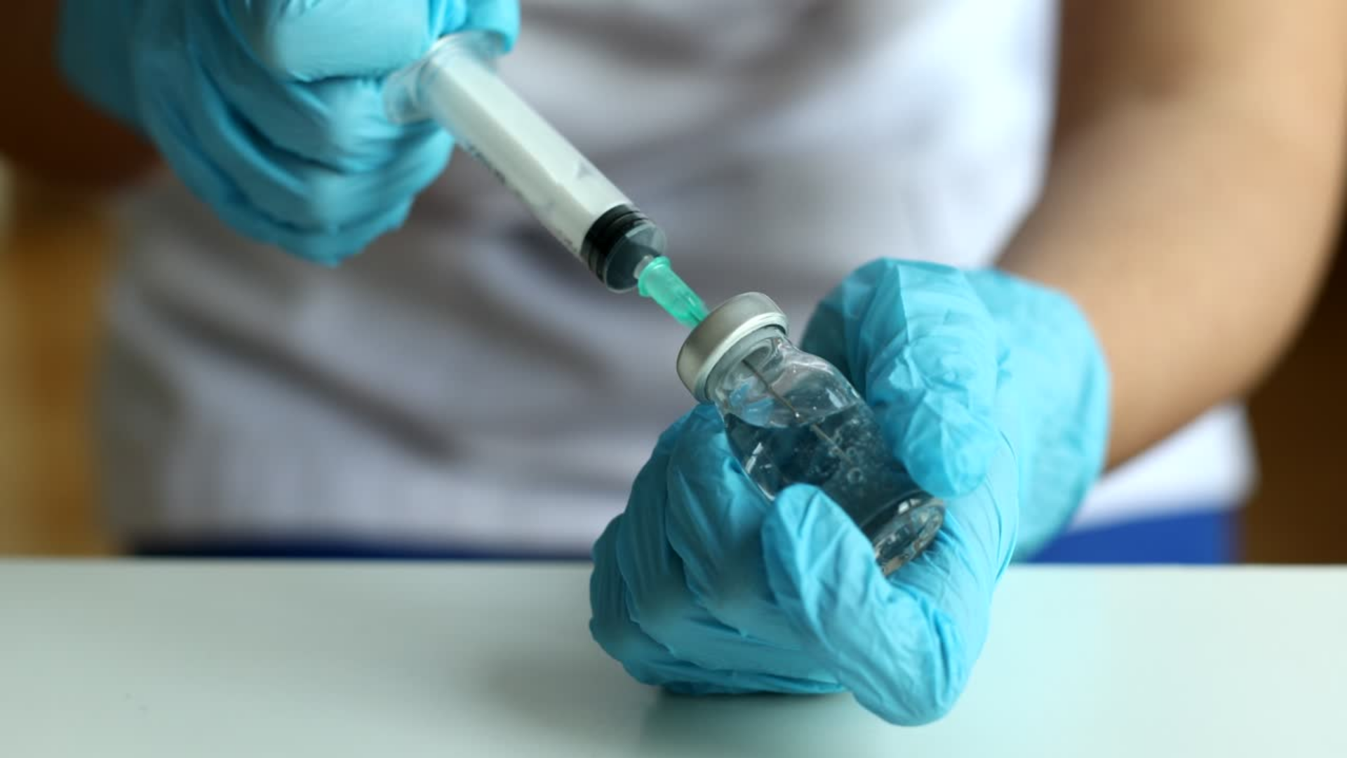 A medical expert transferring the vial's contents to the medical syringe.