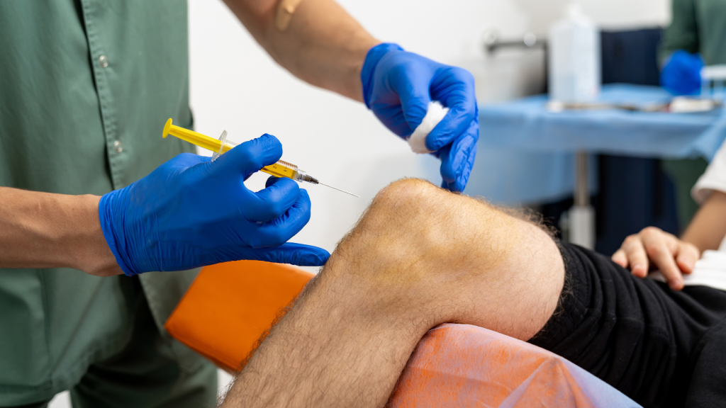 A medical professional administering a knee joint injection to a patient.