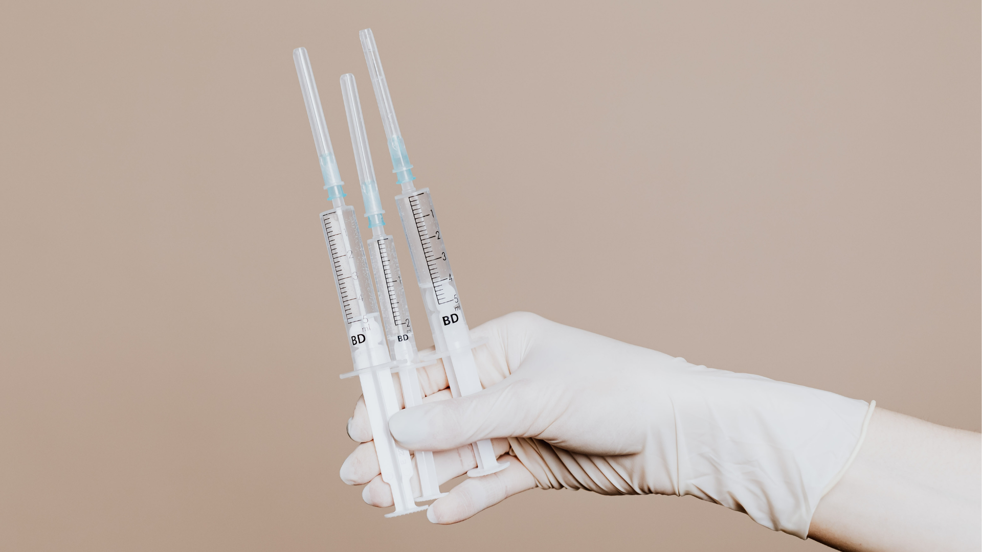 A healthcare provider holding three syringes.