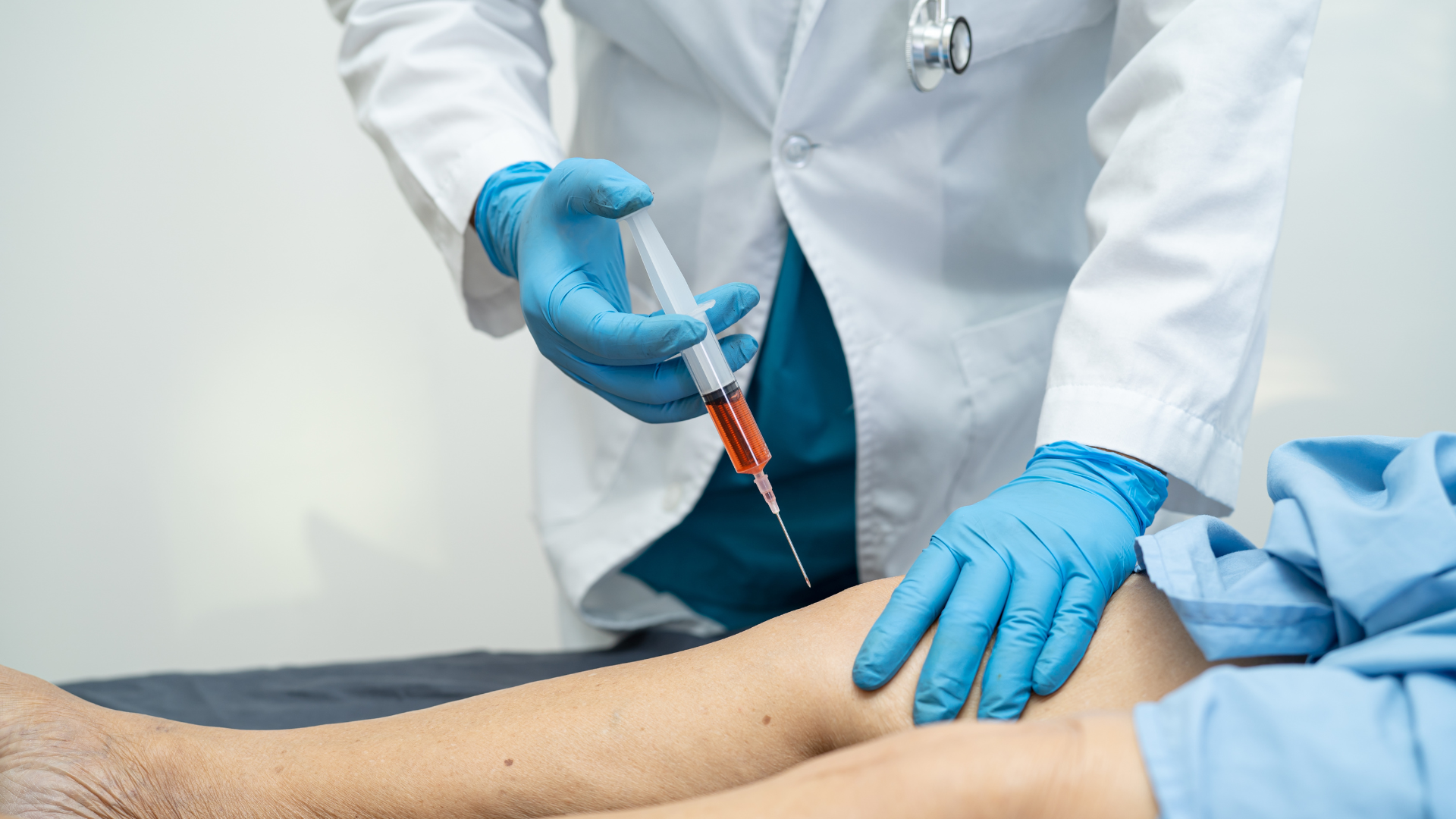 A healthcare provider administering a knee injection into the patient's joint.