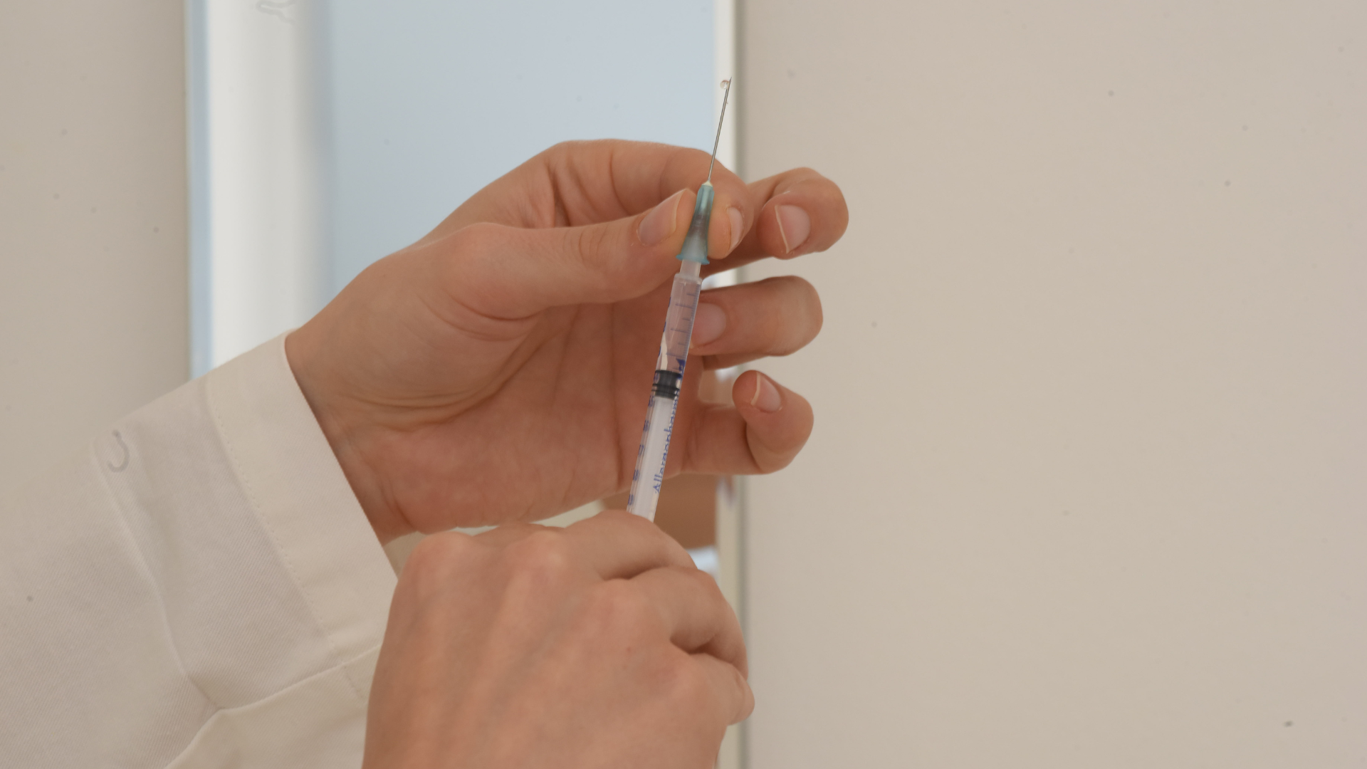 A medical professional holding a medical syringe.