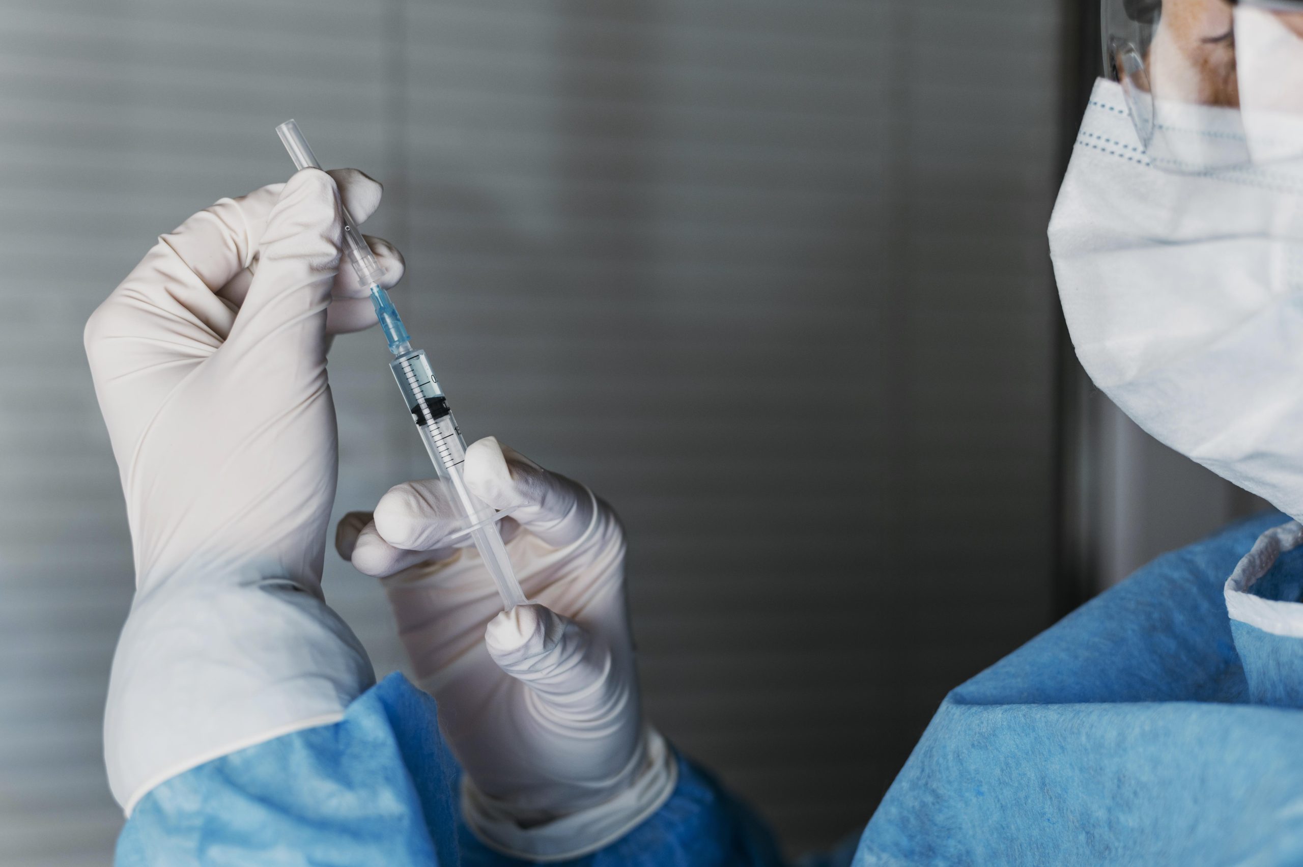 A medical professional transferring the vial's content to the syringe.