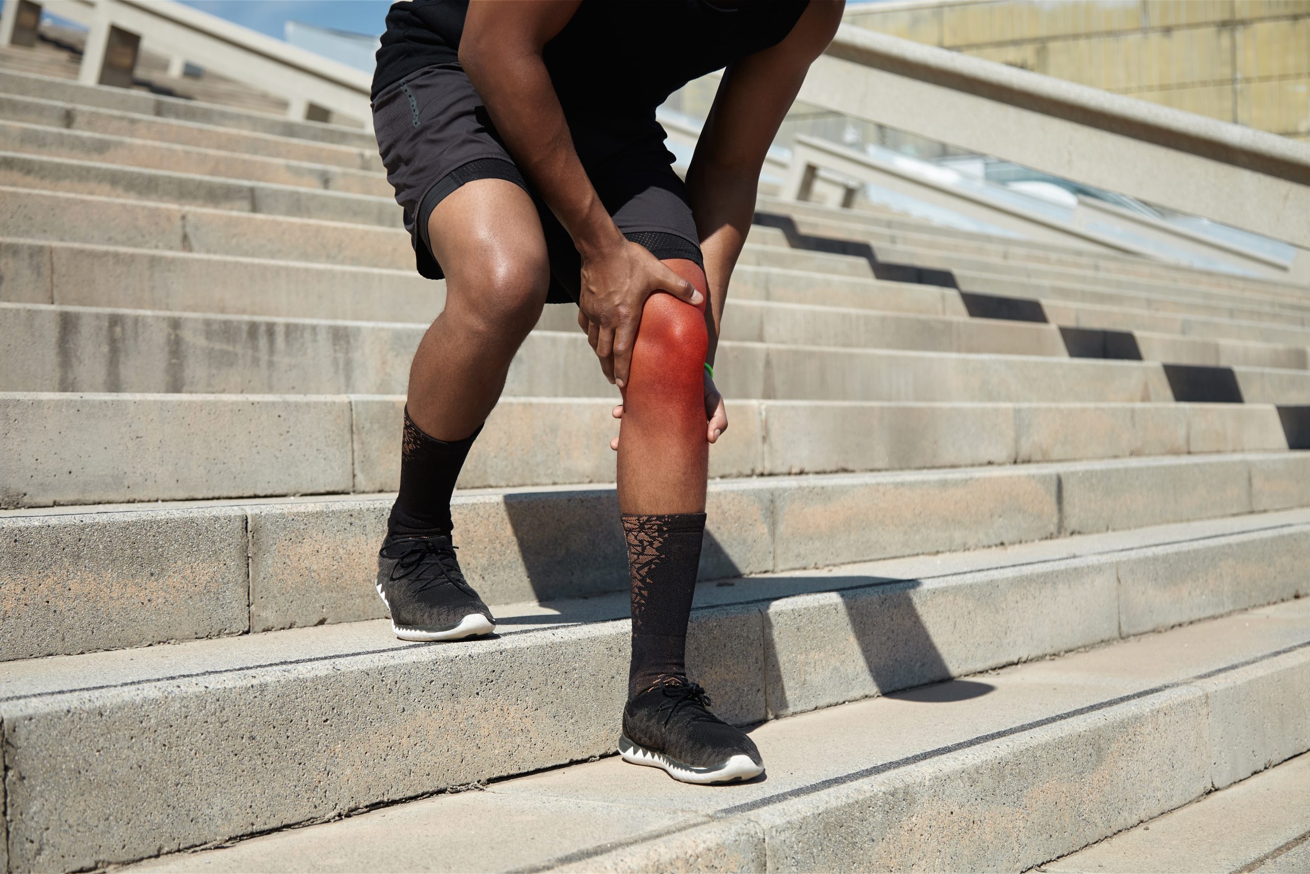 An individual suffering from knee pain going down the stairs.