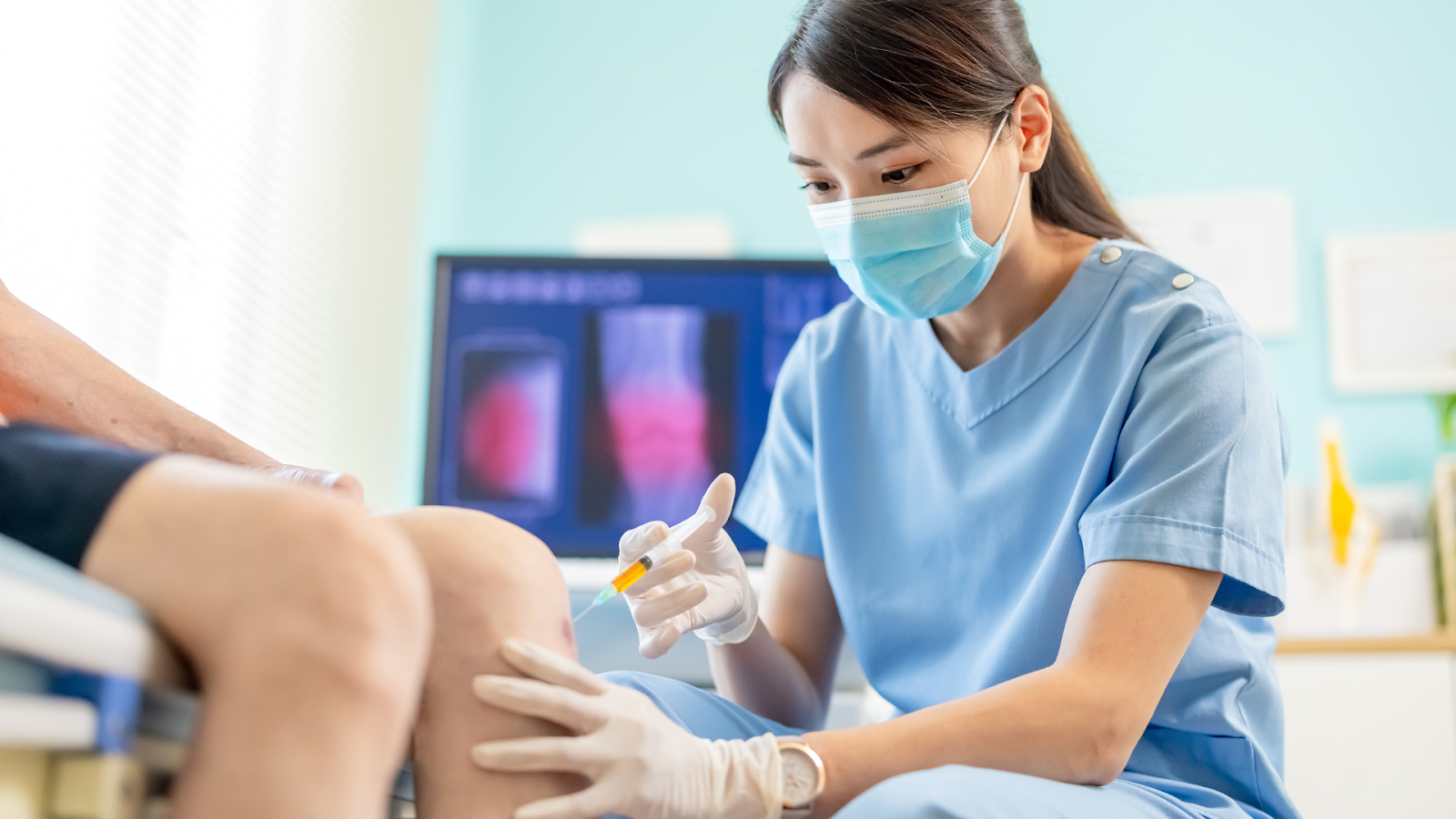 A medical practitioner administering an injection into a patient's knee joint.