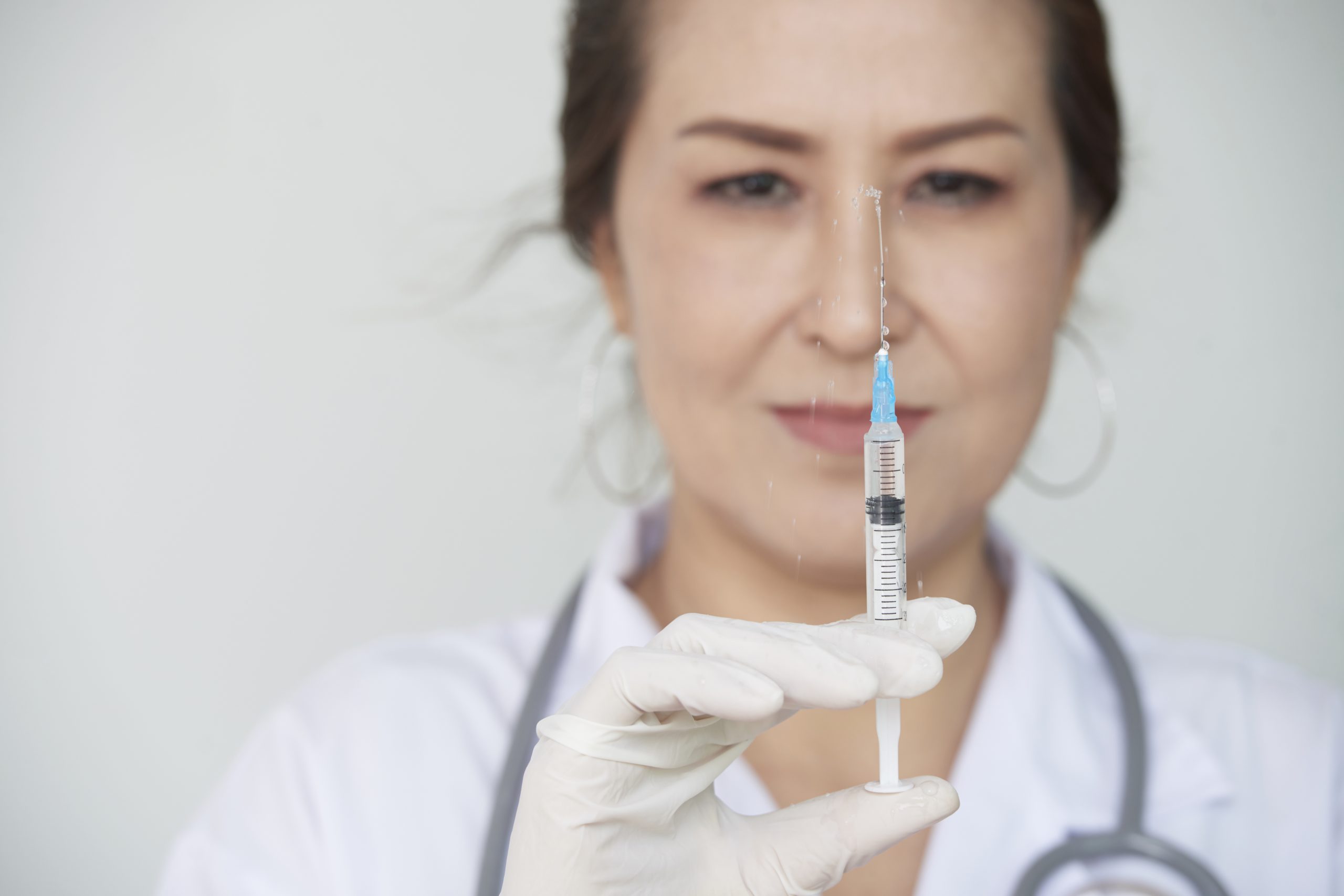 A healthcare provider holding a medical syringe.