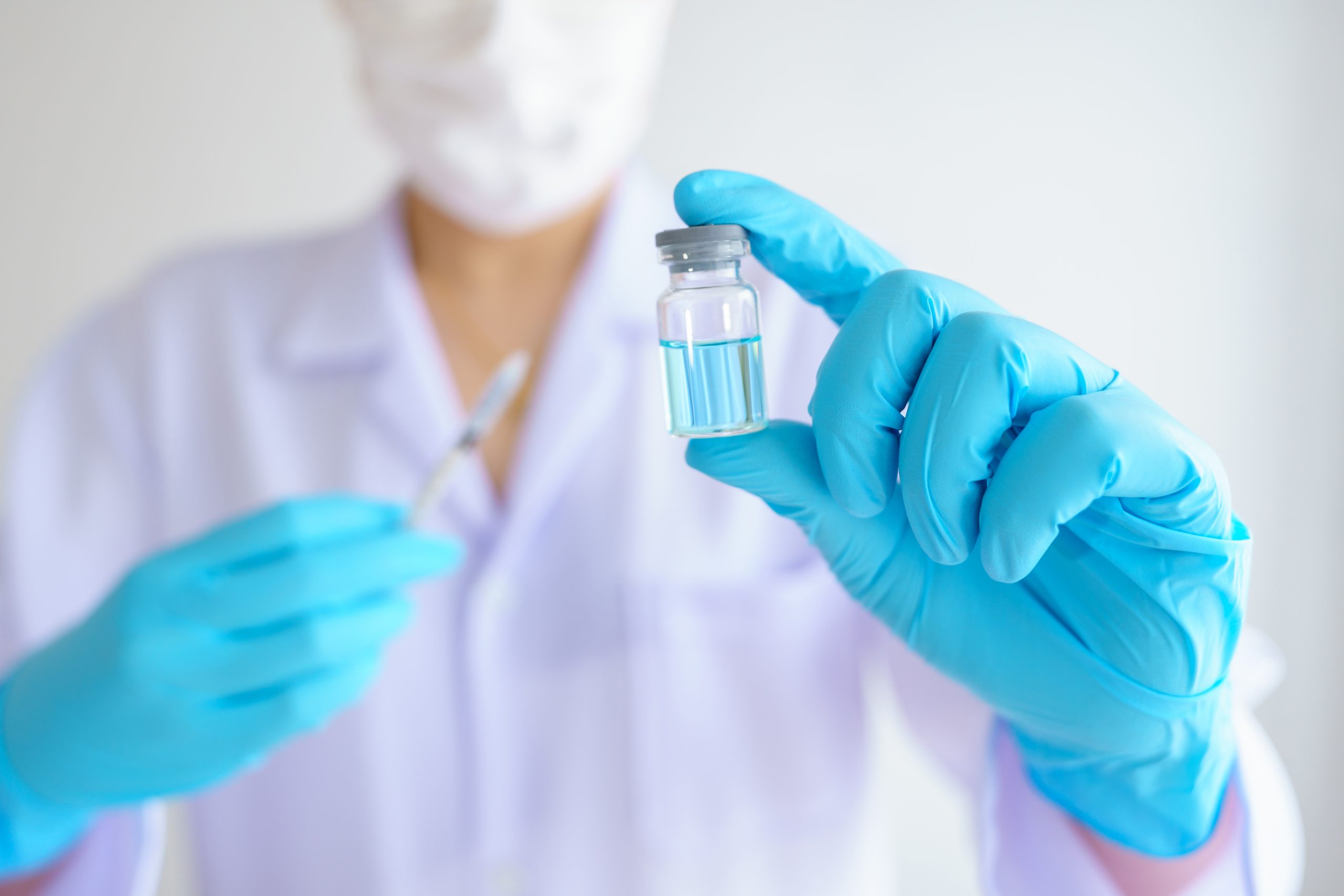 A medical professional holding a solution vial and injection syringe.