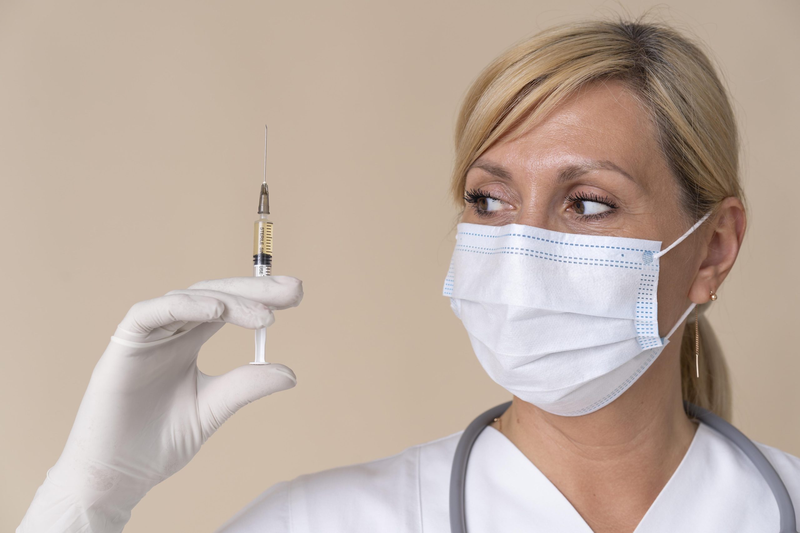 A healthcare professional holding a medical syringe.