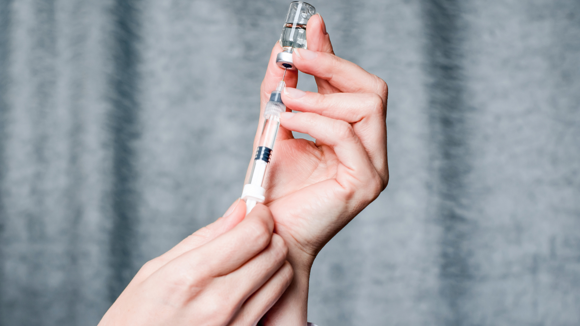 A medical professional filling the syringe with the entire contents of the vial.