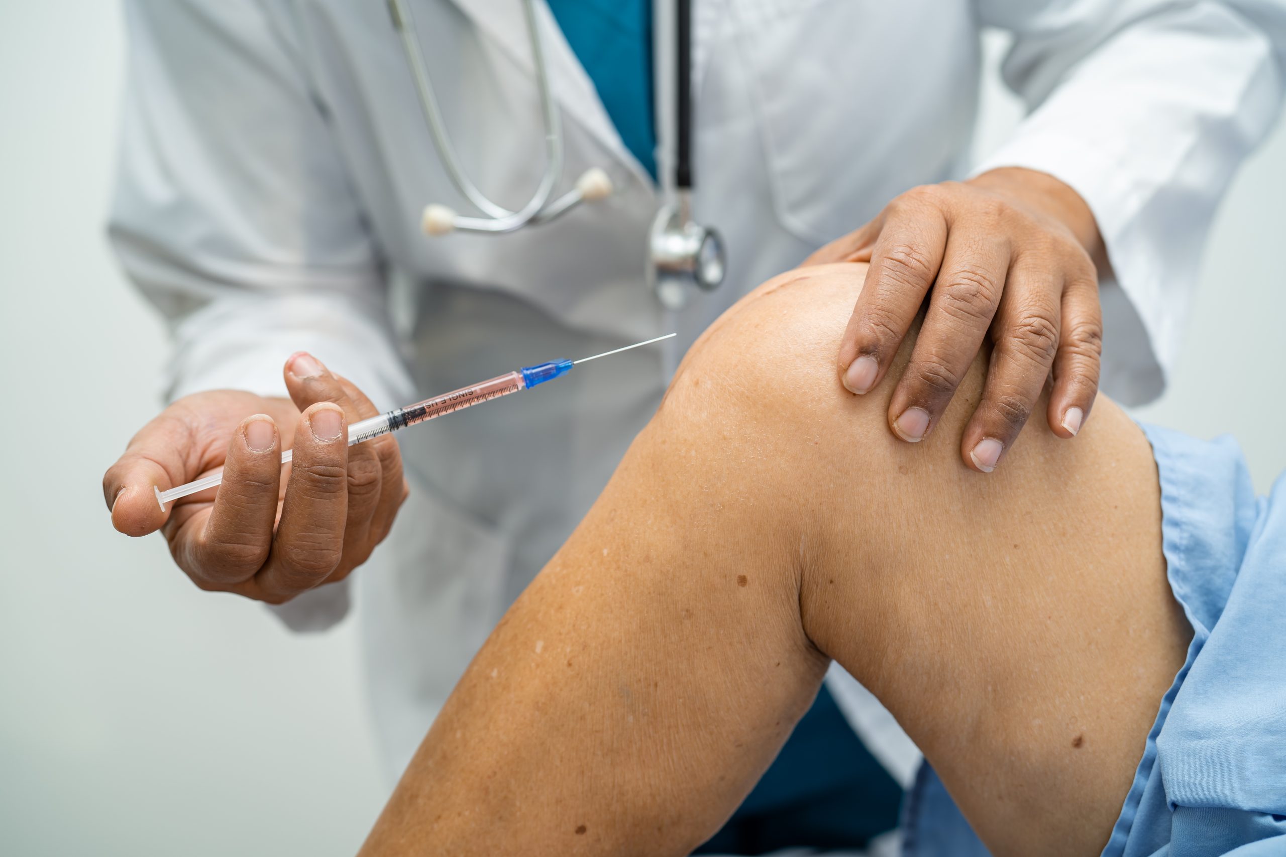 A healthcare provider administering a knee injection.