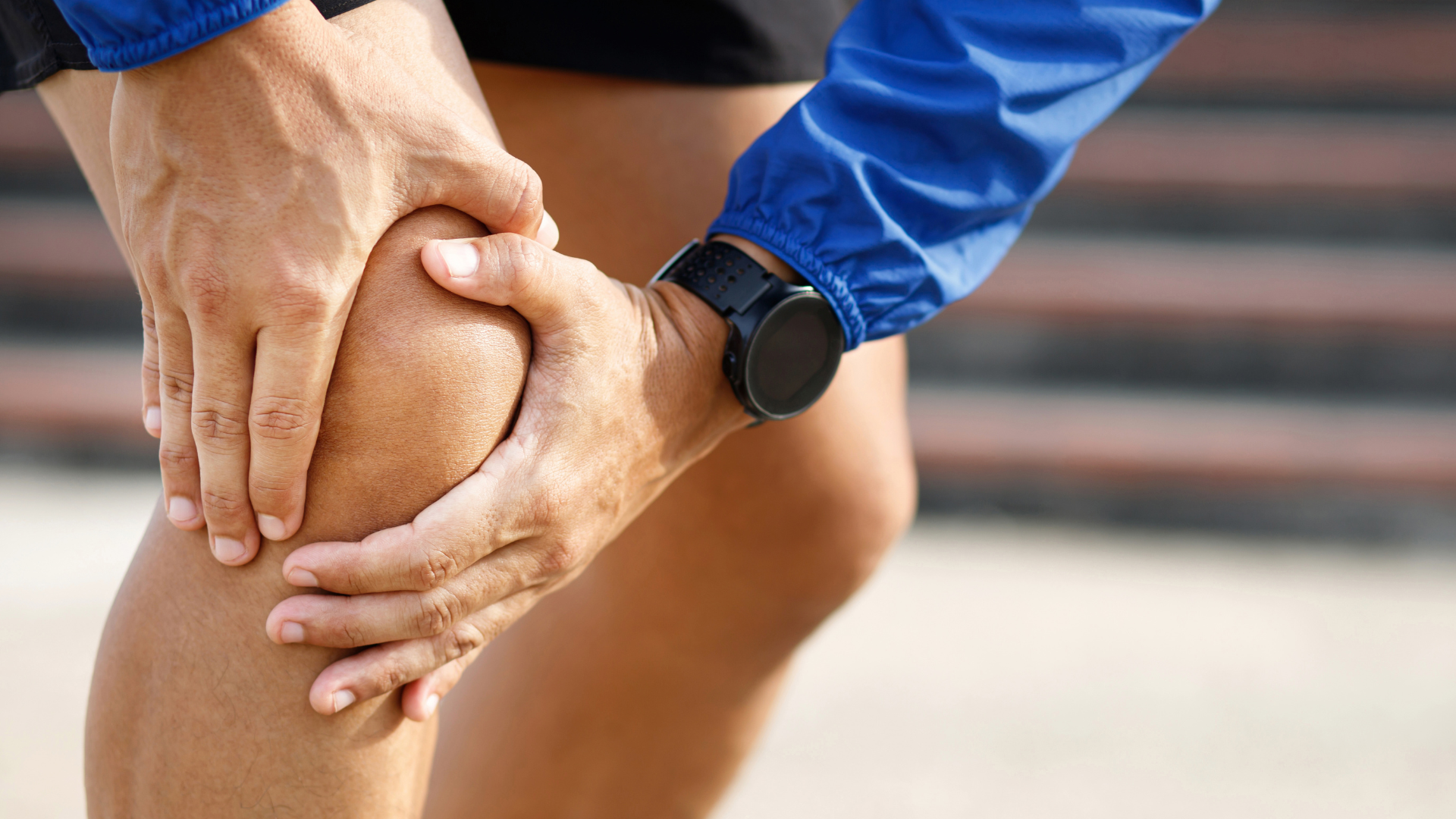 An individual holding their knee while suffering from a knee joint pain.