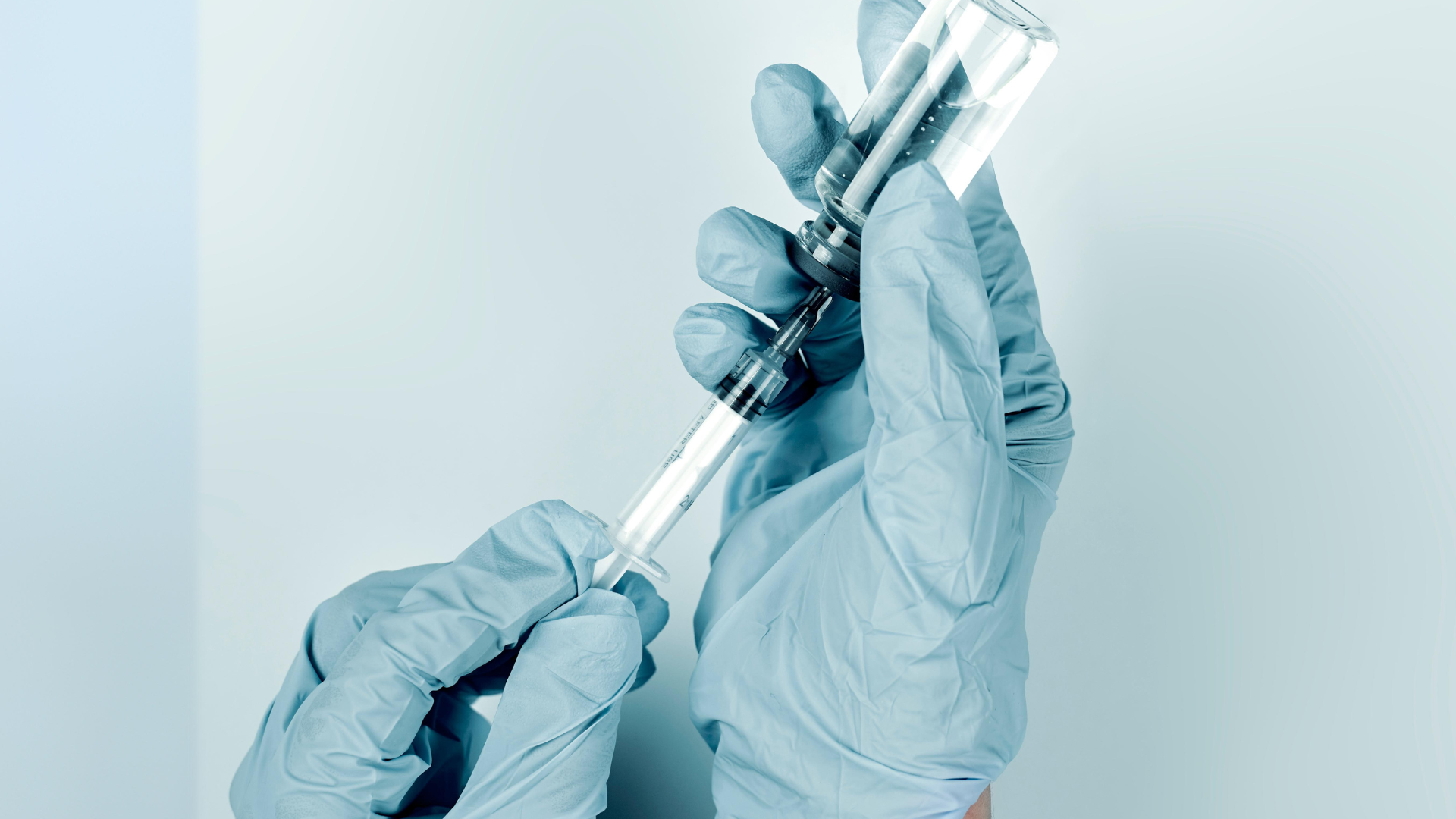 A healthcare provider filling the syringe with the vial's content.