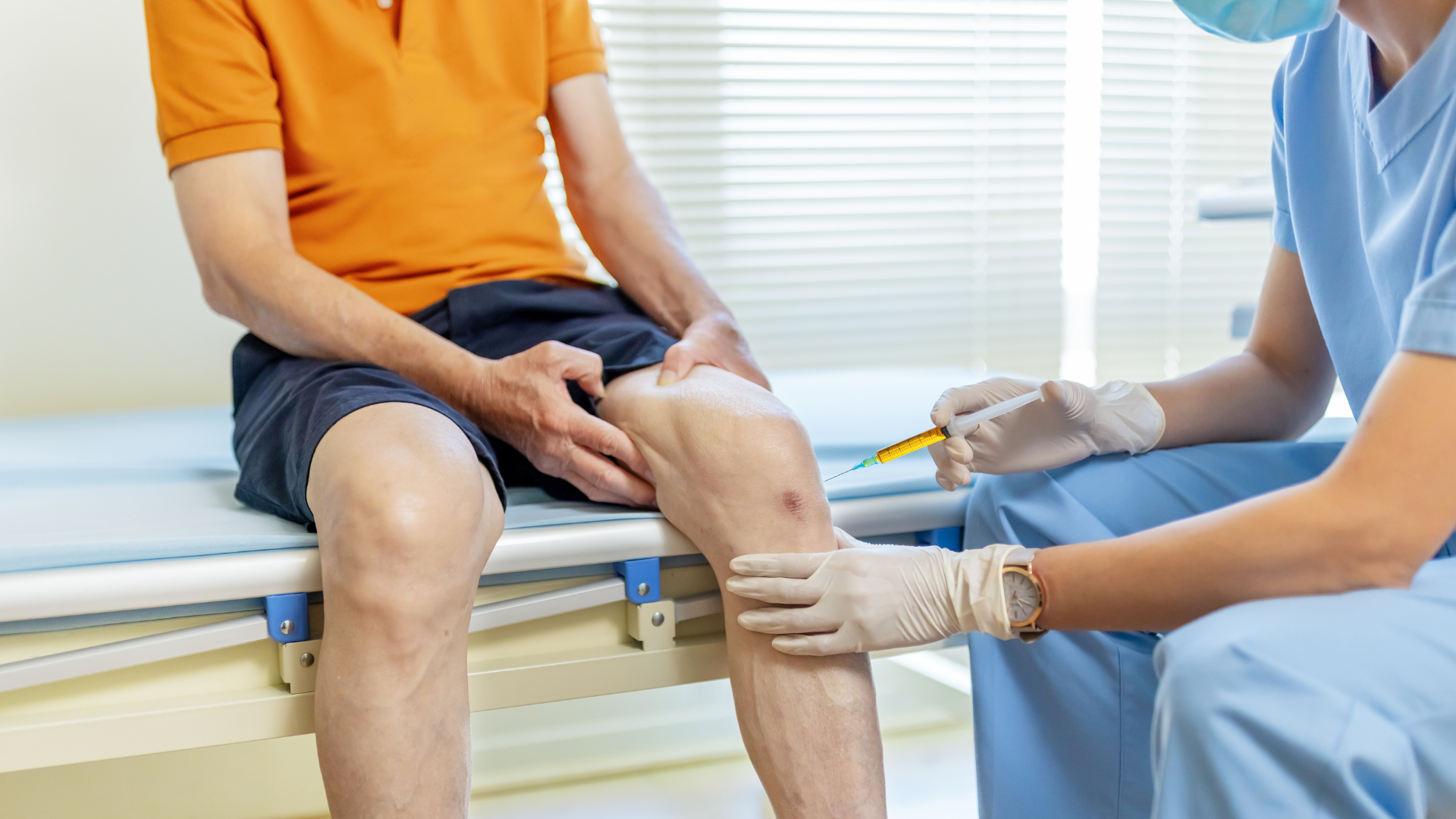 A medical practitioner administering knee injection into the patient's knee.