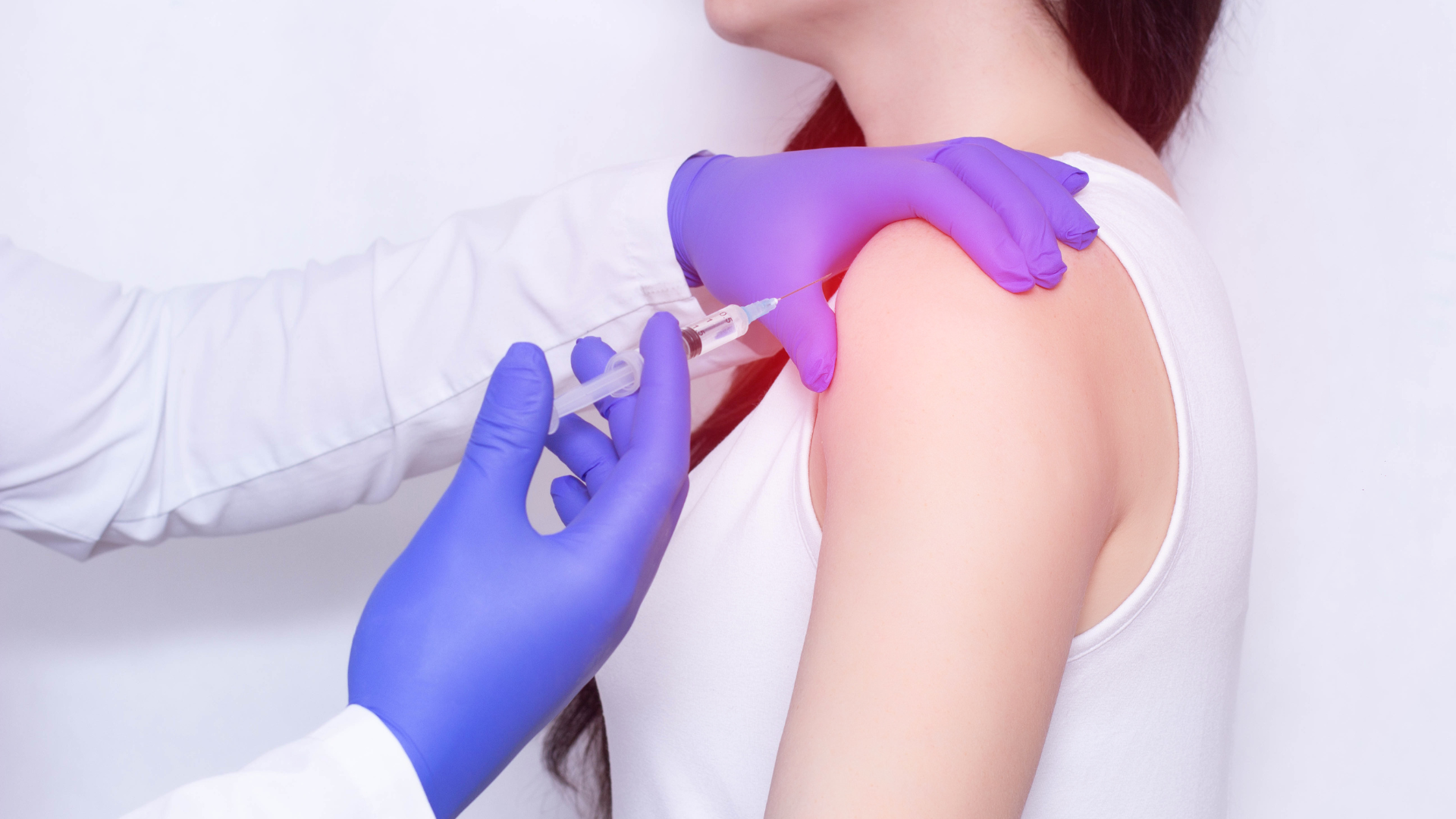 A medical professional administering an injection into the patient's shoulder joint.