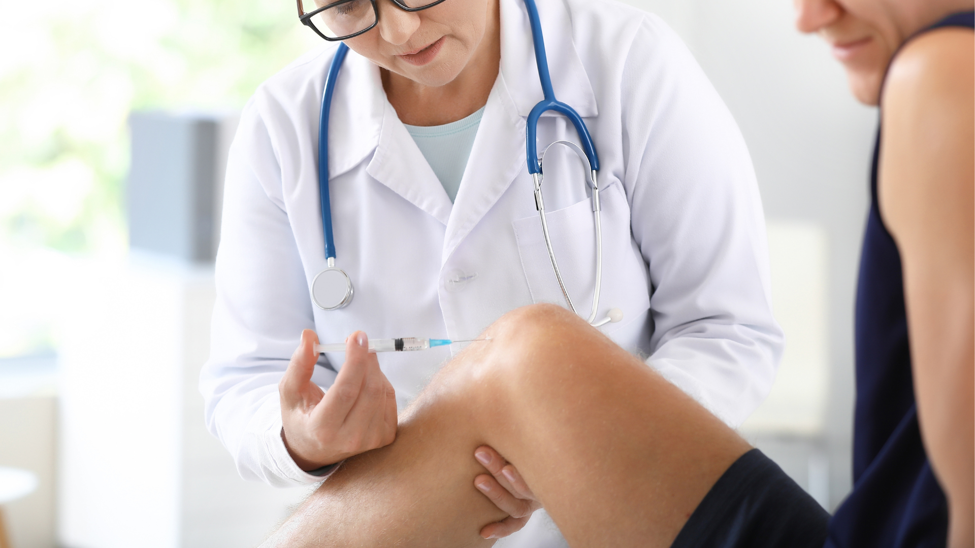 A healthcare provider administering a knee injection to an individual.