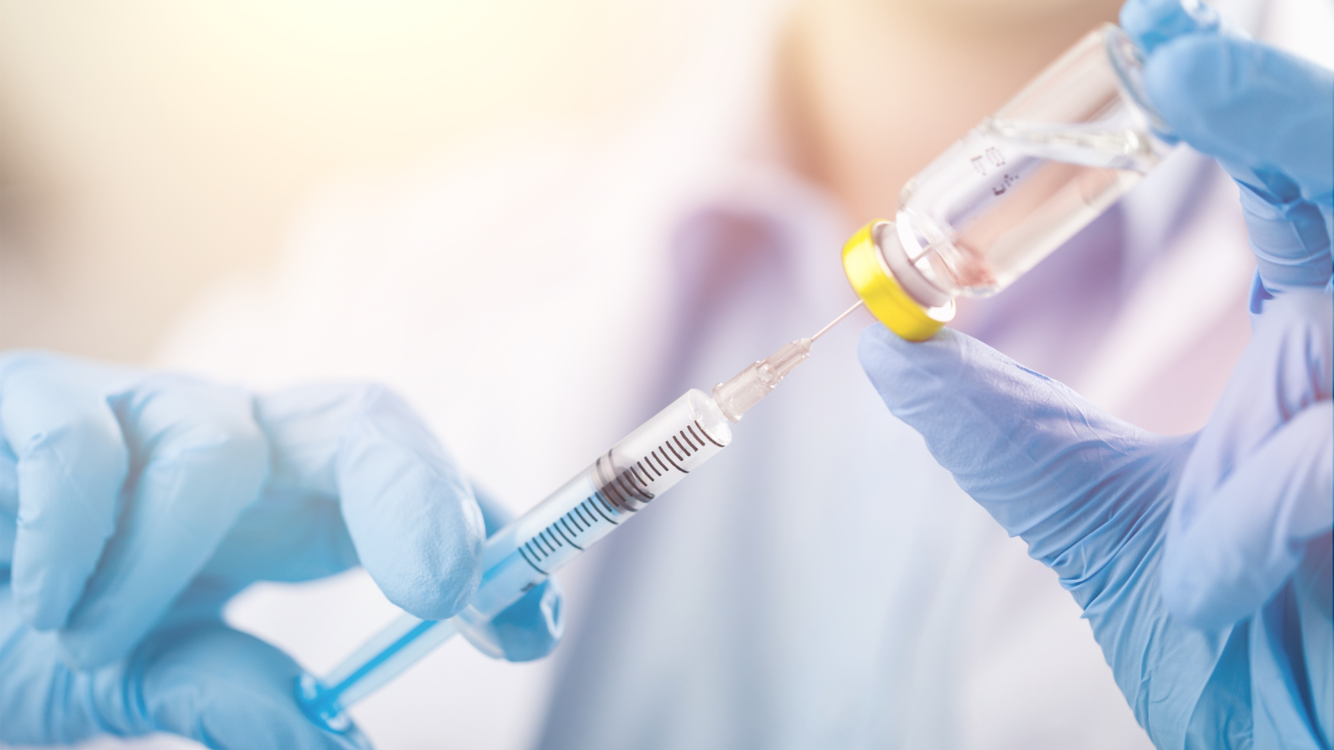 A healthcare provider transferring the vial contents into the syringe.