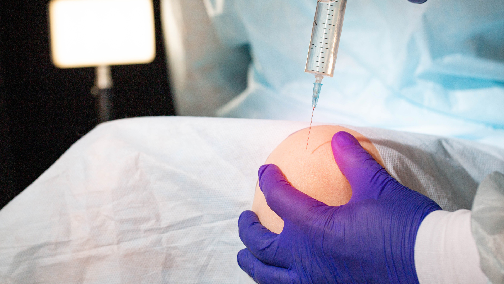 A healthcare provider injecting a solution into the patient's knee.