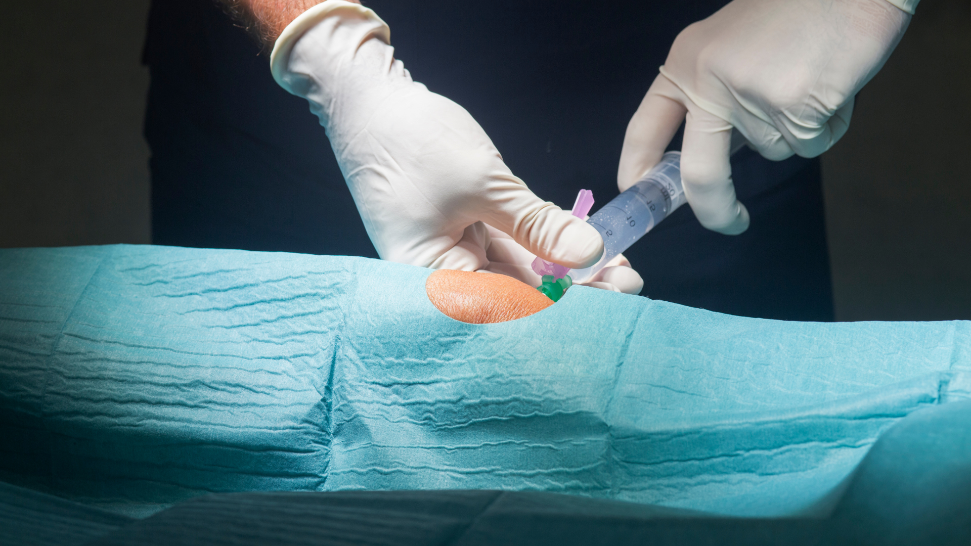 A medical professional administering an injection into the patient's knee.