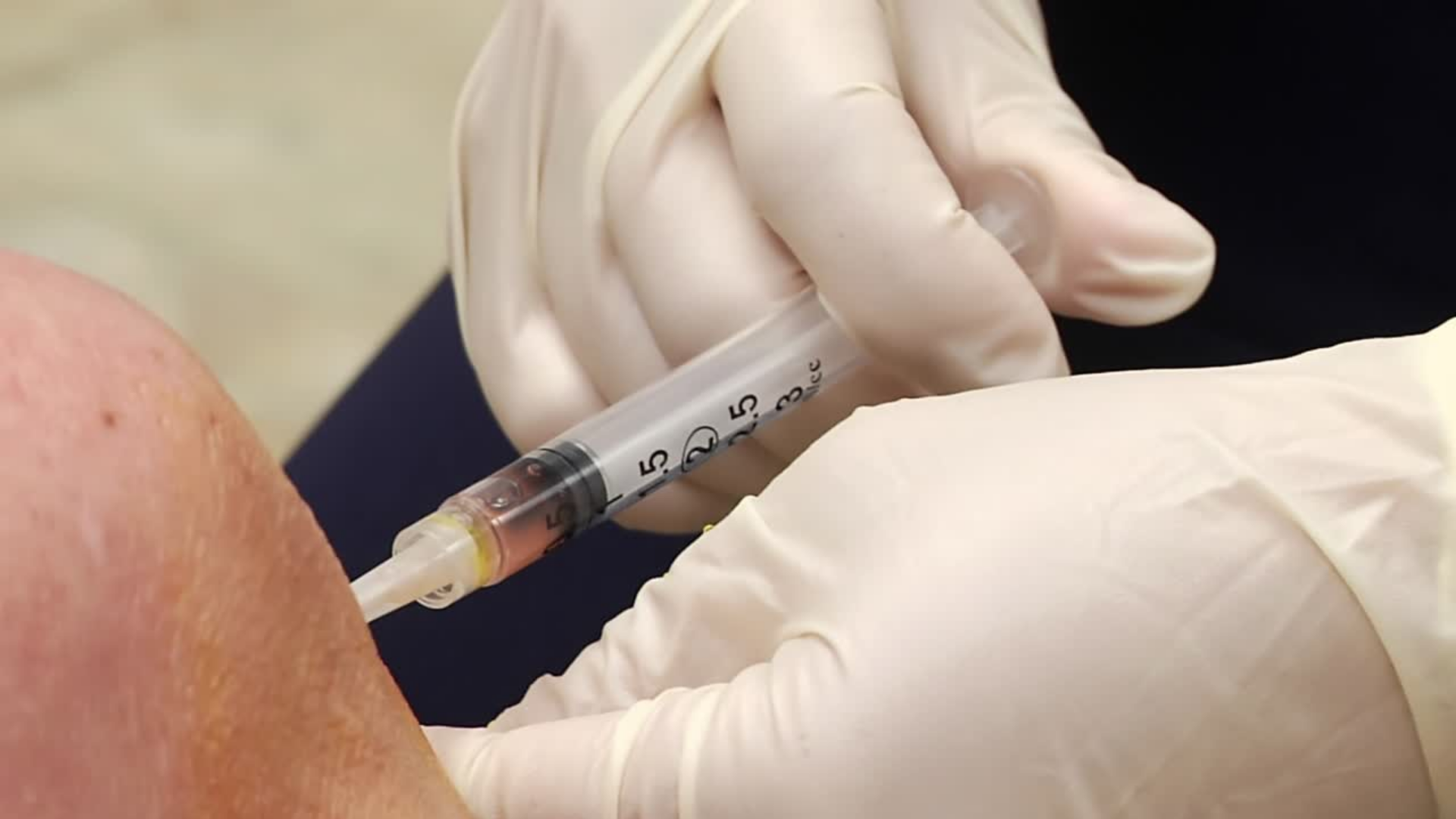 A medical professional administering knee injection into the patient's knee.