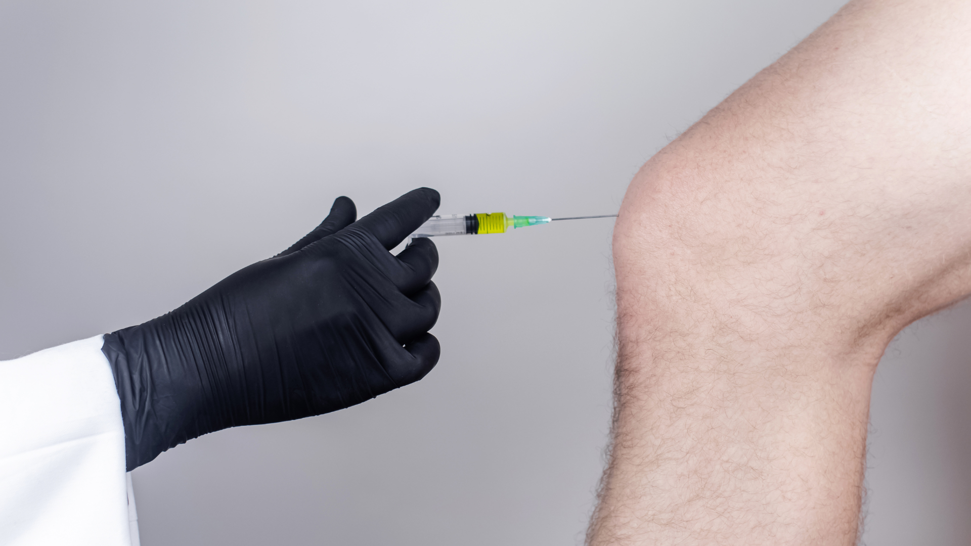 A medical professional administering a knee injection.