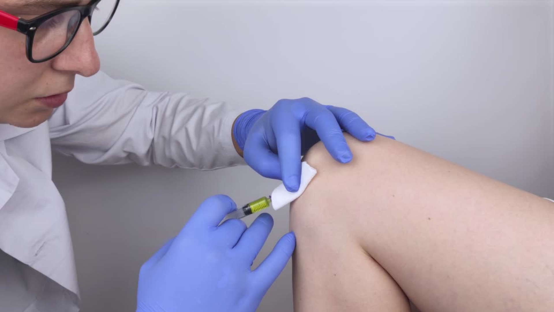 A healthcare provider administering a knee injection.