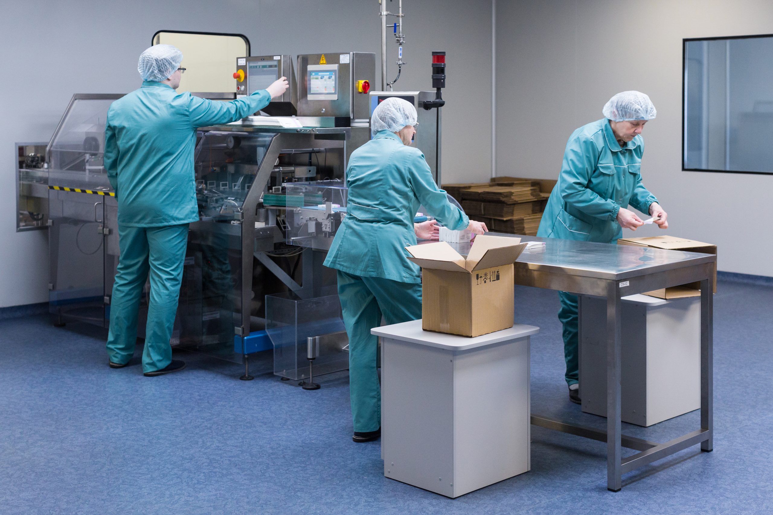 Pharmaceutical technicians work in sterile working conditions at pharmaceutical factory.