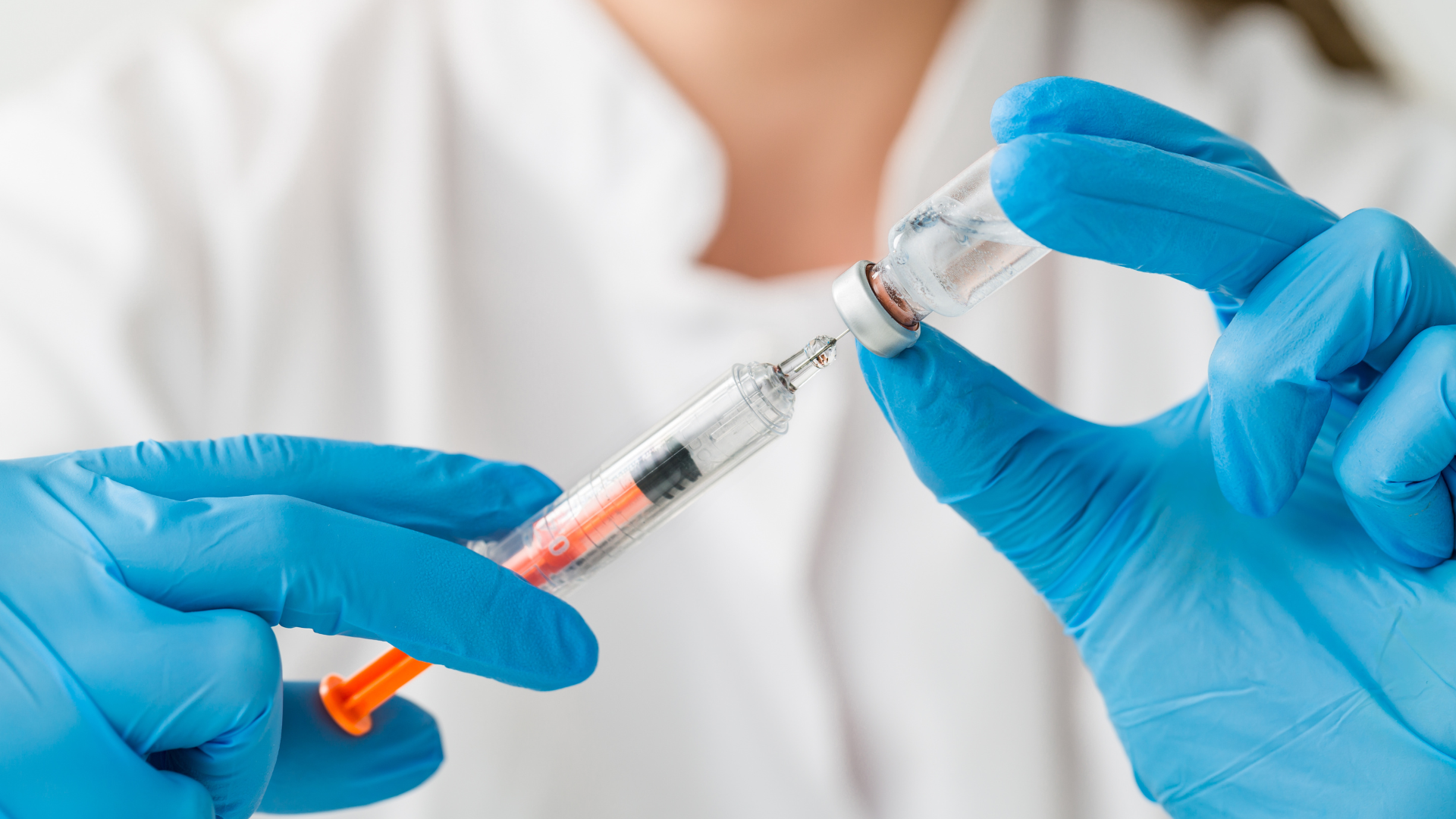 A healthcare provider transferring the vial contents into the syringe.