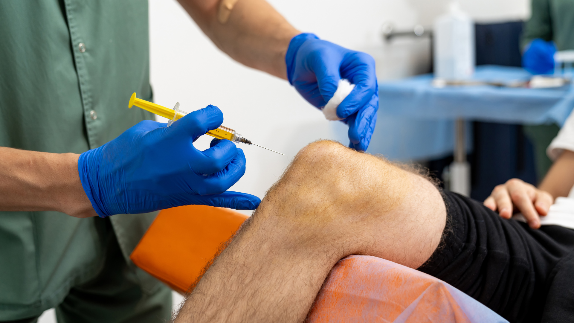 A medical professional administering a knee injection into the patient.