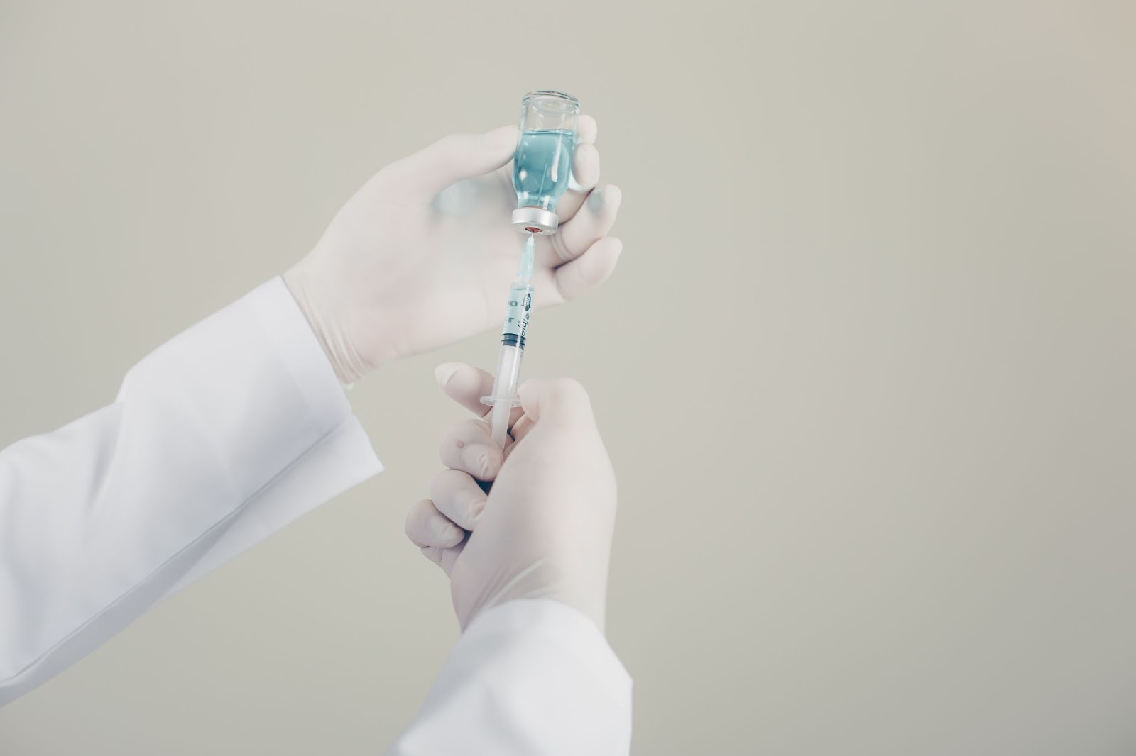 A medical professional filling the syringe with a solution.