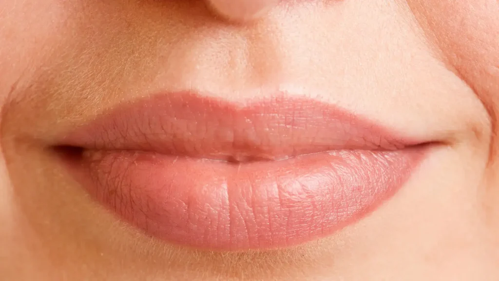 An individual smiling and flexing their lips.