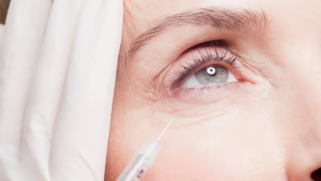 A medical professional administering an injection to a patient's under eye.