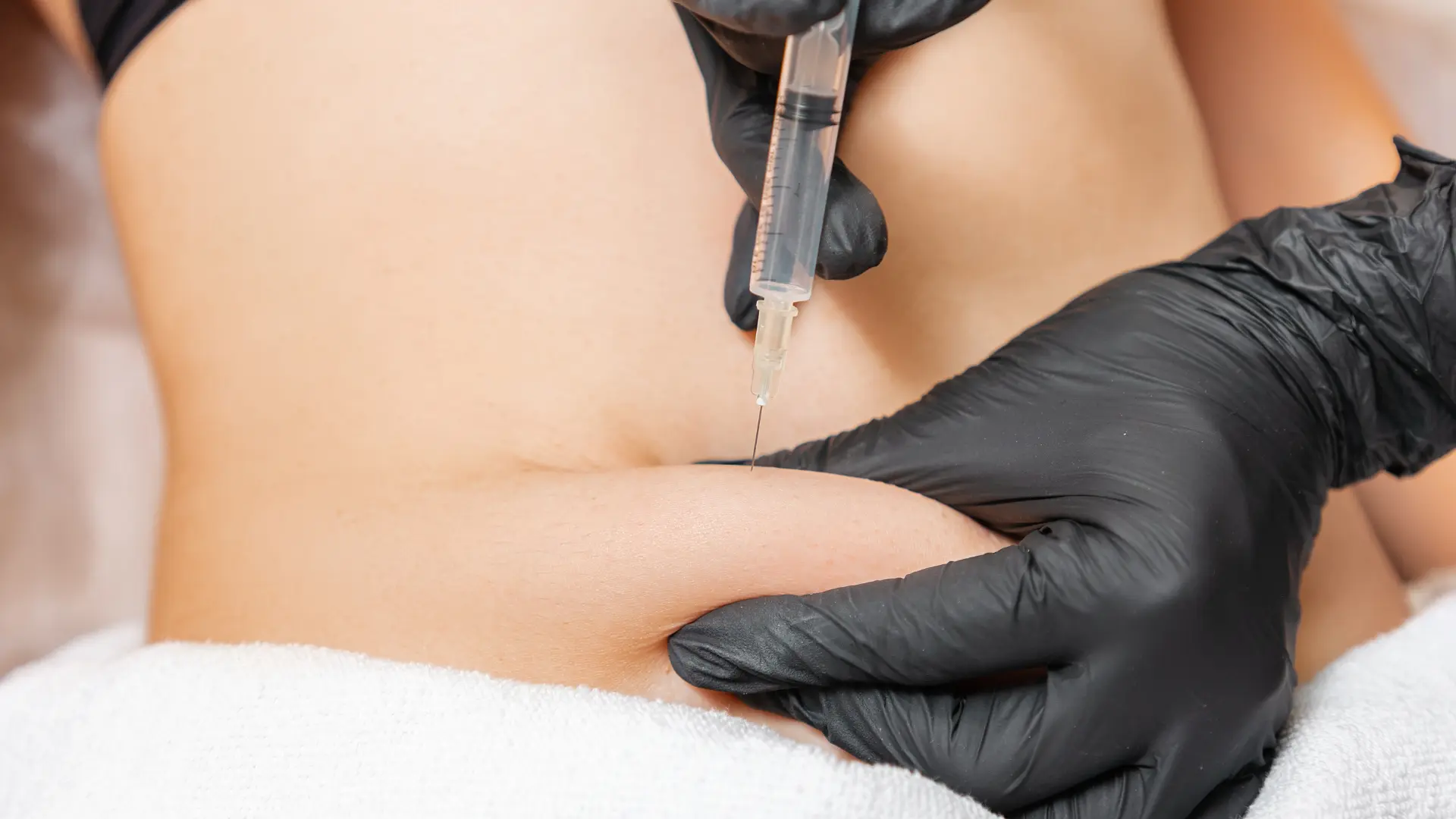 A medical professional administering an injection to a patient's abdomen.