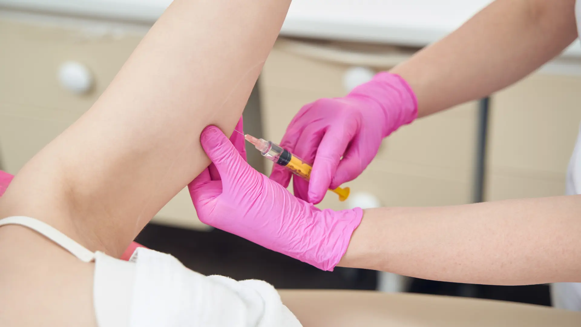 A medical profesisonal administering an injection to a patient's inner arms.