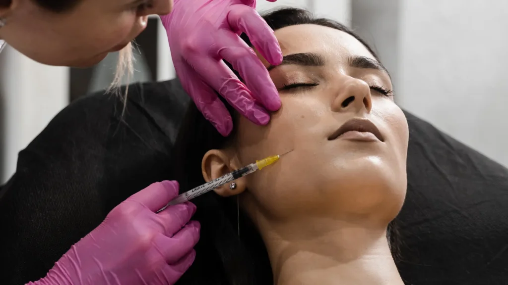 A medical professional administering an injection the patient's cheek region.